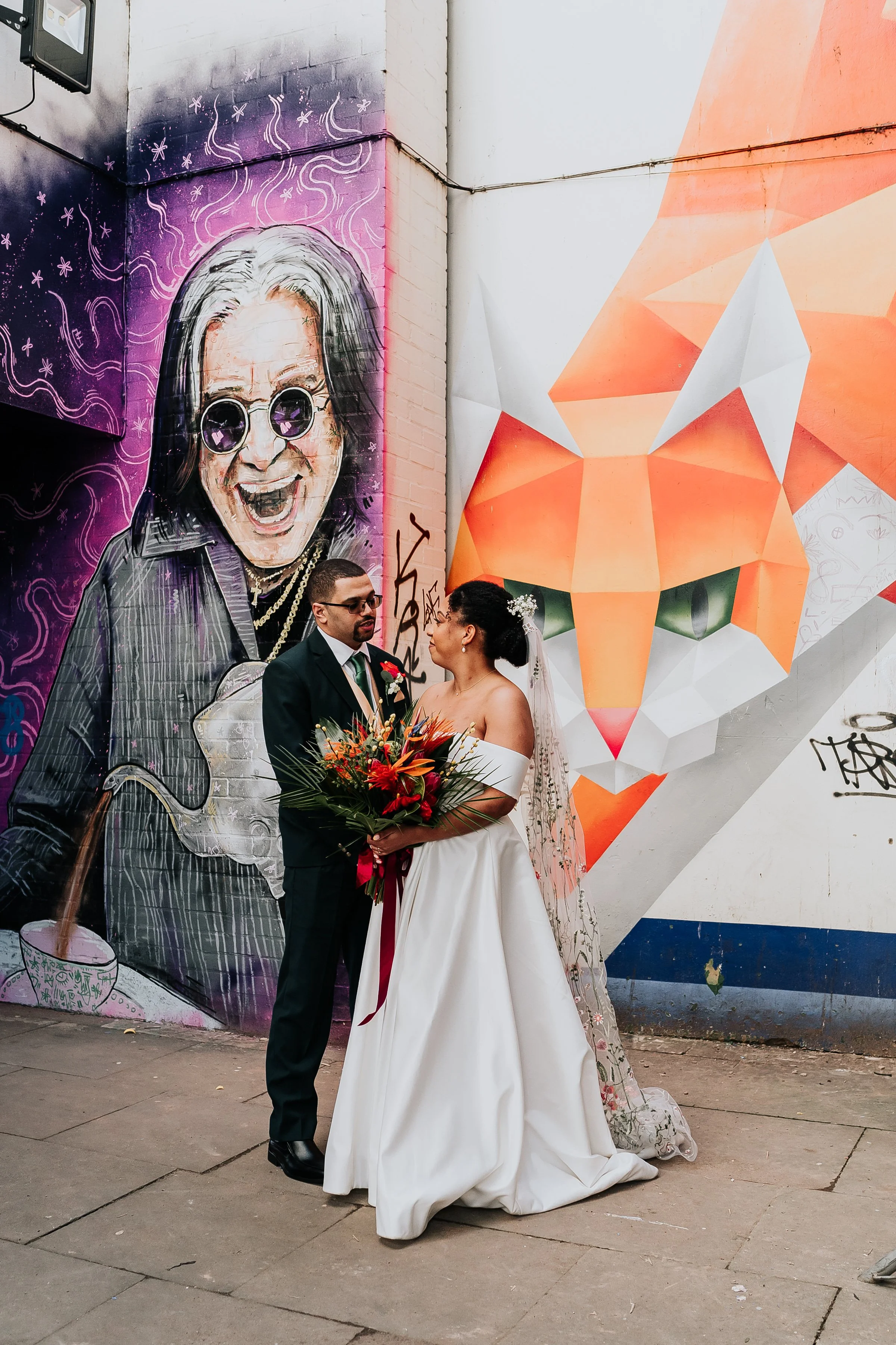 bride and groom talking in front of graffiti for their wedding photo