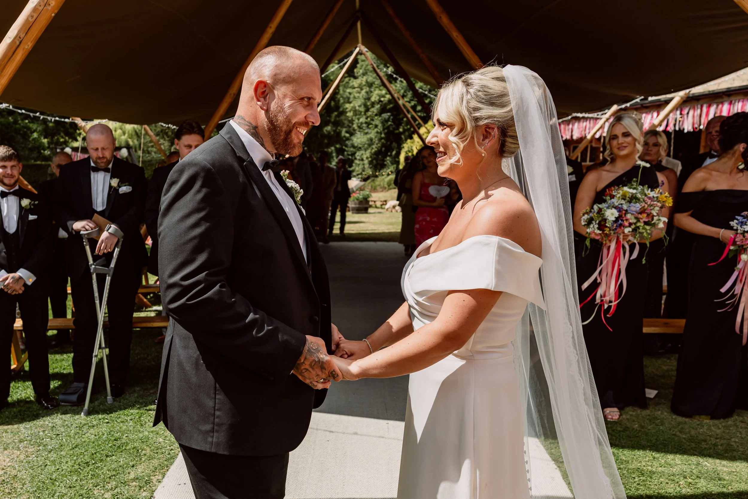 Bride and groom holding hands and smiling at each other during their wedding ceremony on their wedding day in birmingham