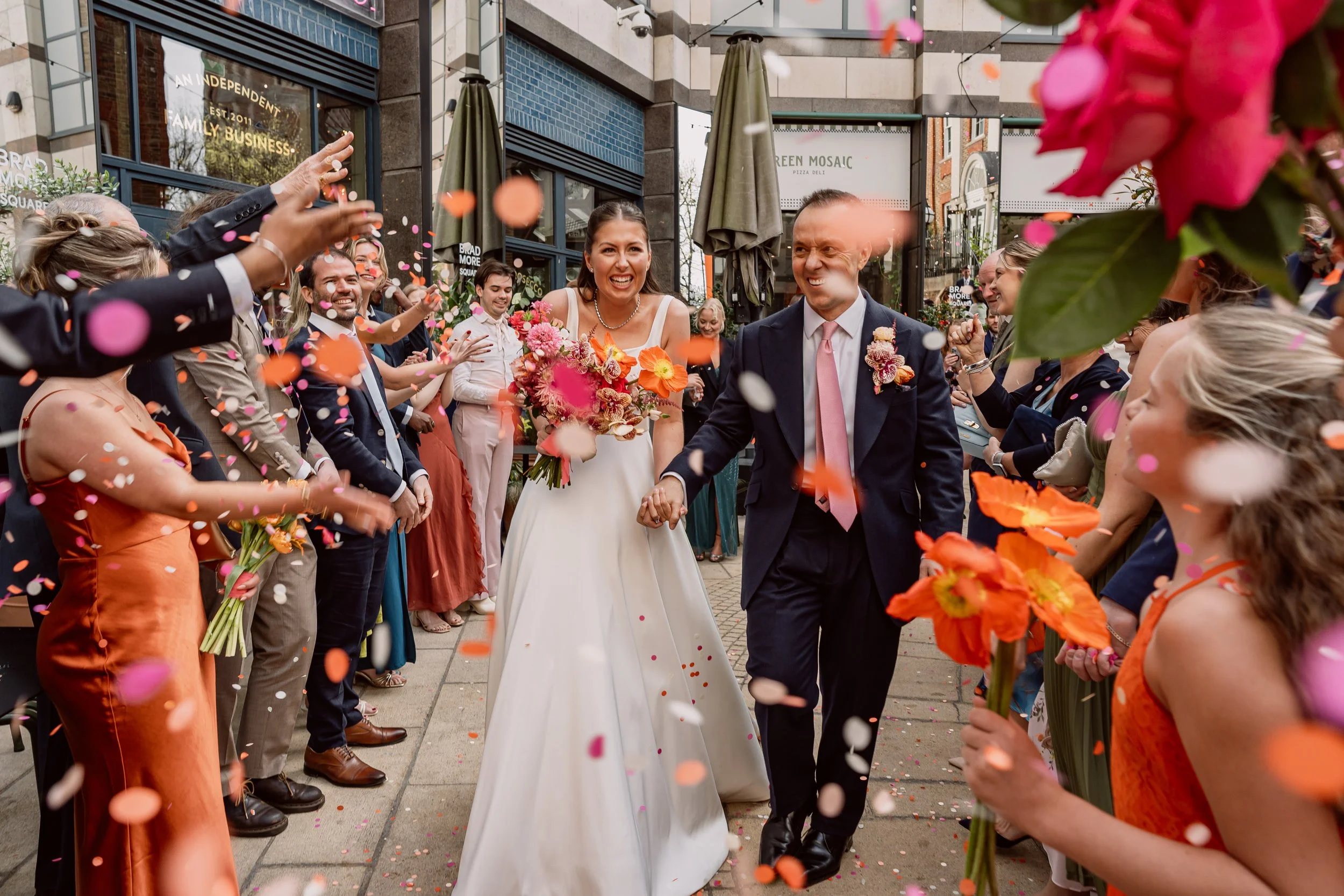 Bride and groom walking through colourful confetti captured in Steph's alternative wedding photography style
