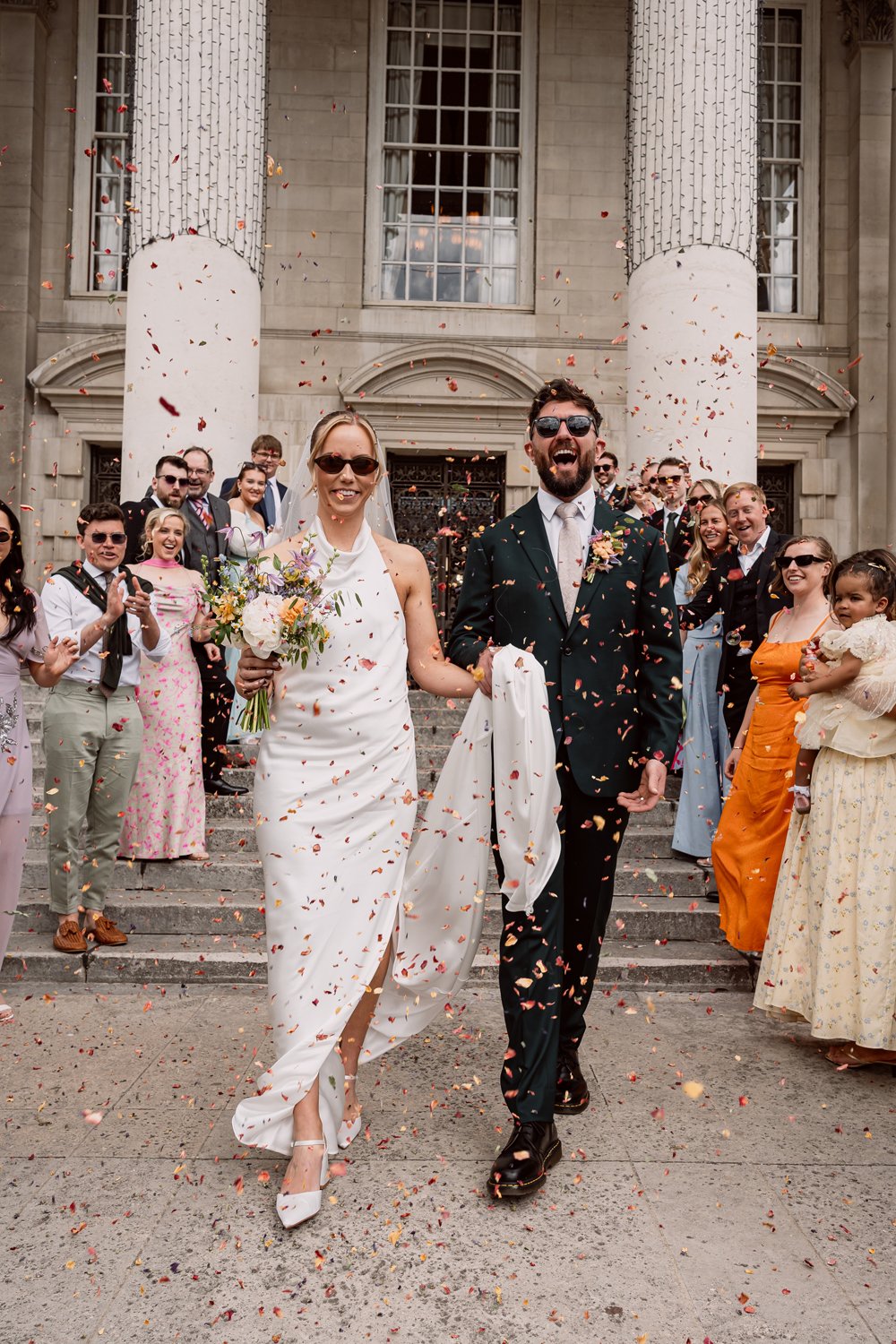 Bride and groom laughing through confetti on their wedding day in Leeds captured by Alternative wedding photographer