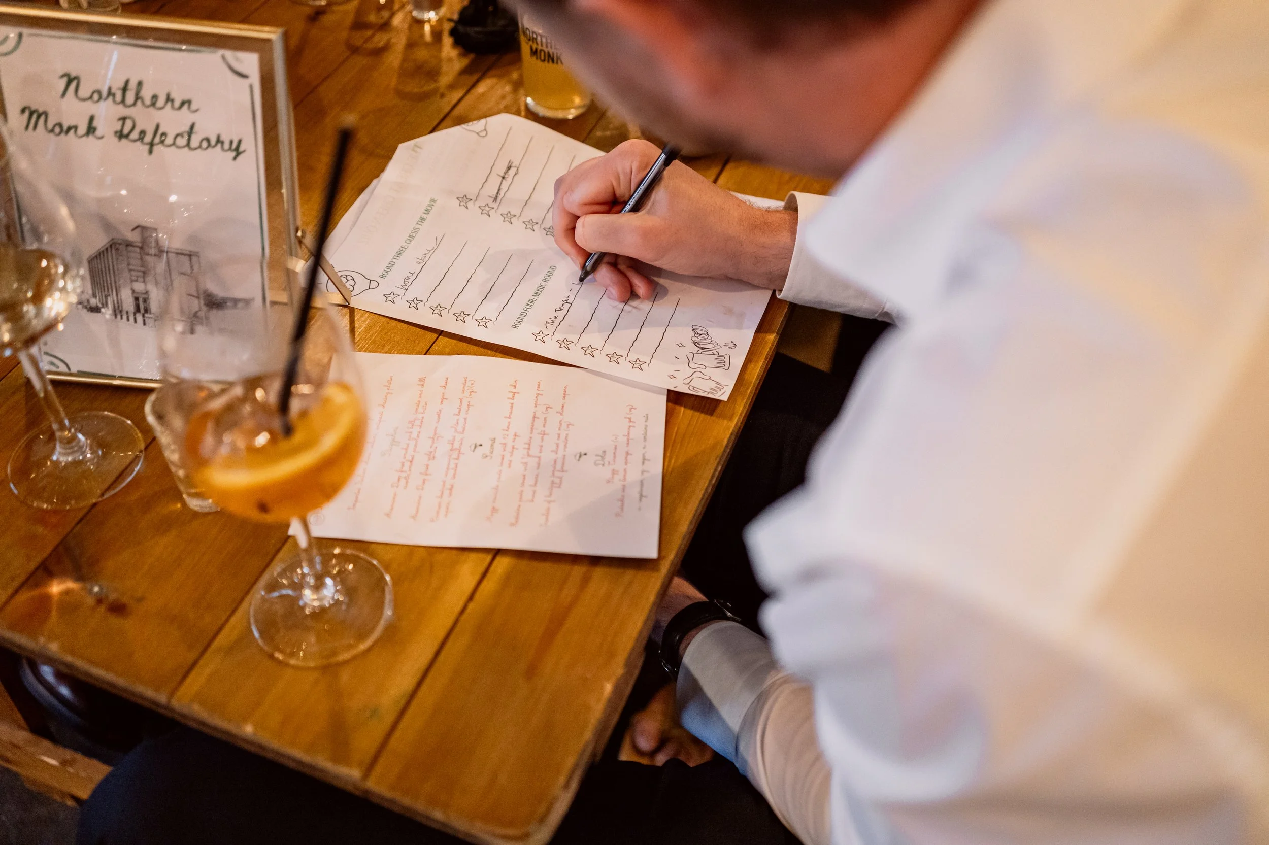 Candid photo of guest doing pub quiz on wedding day at Chapter Hall in Leeds