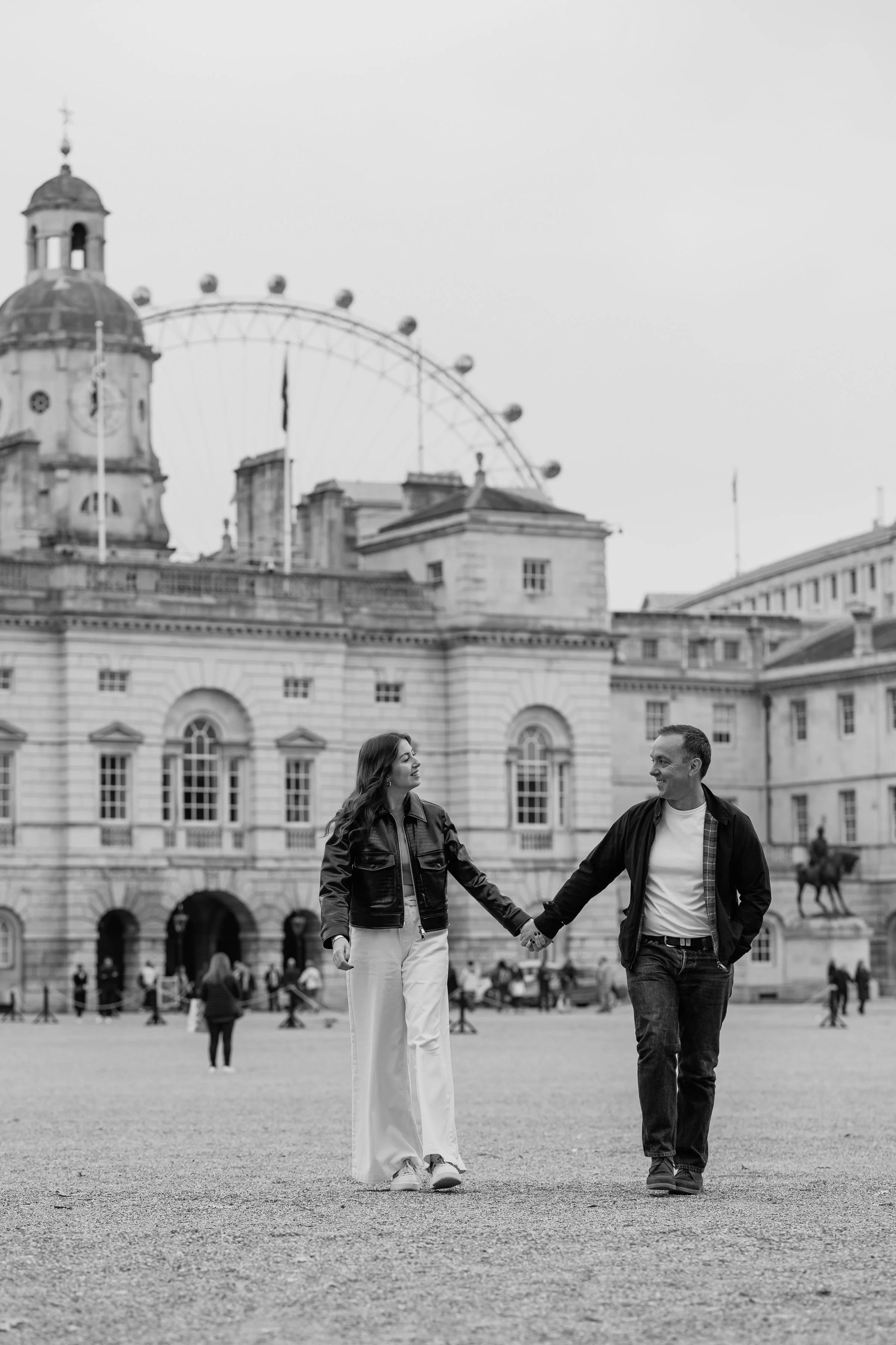 Couple holding hands walking in London with the London Eye in the background and captured by London photographer