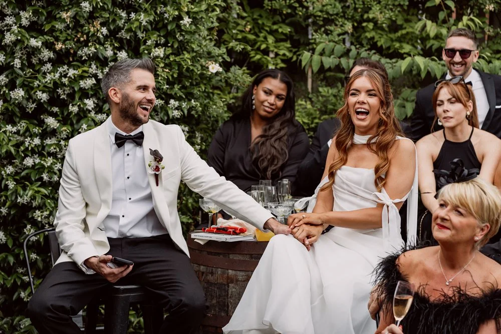 bride and groom laughing during speeches on their wedding day