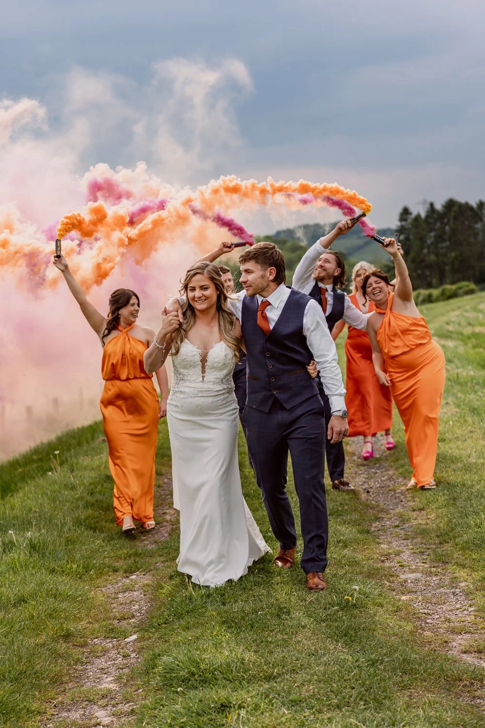 Bride and groom walking with guests and smoke grenades on their wedding day in Birmingham captured by Alternative wedding photographer 