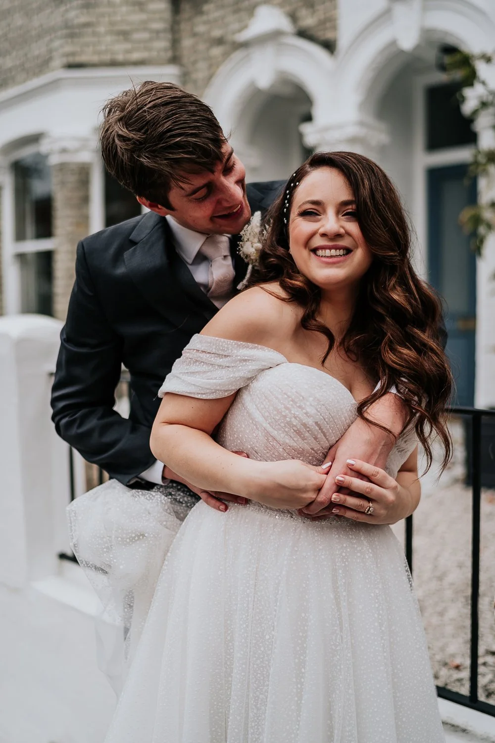 Bride and groom hugging in front of terrace house in London