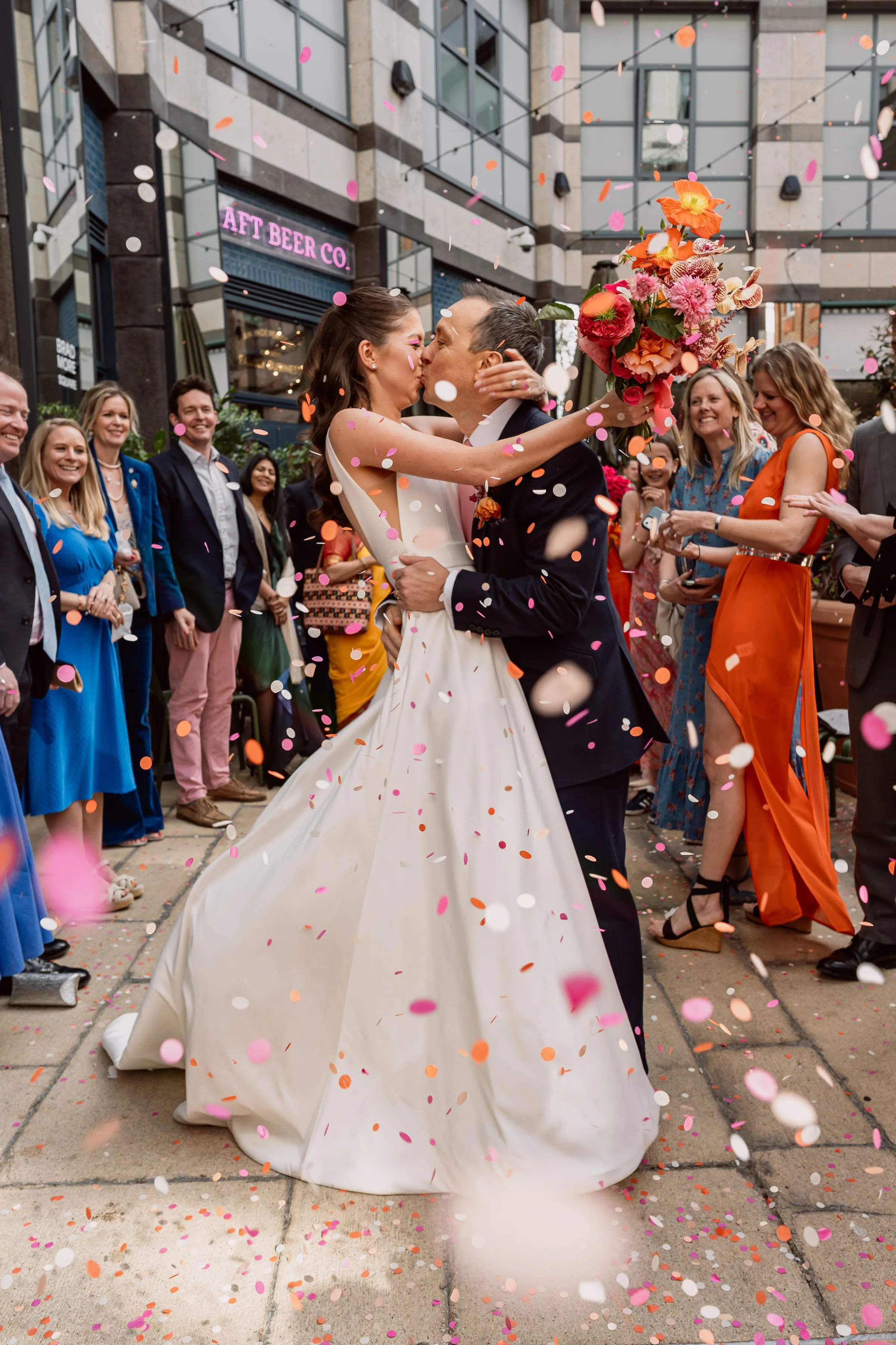 Bride and groom kissing with confetti around them on their wedding day at Kindred in Hammersmith