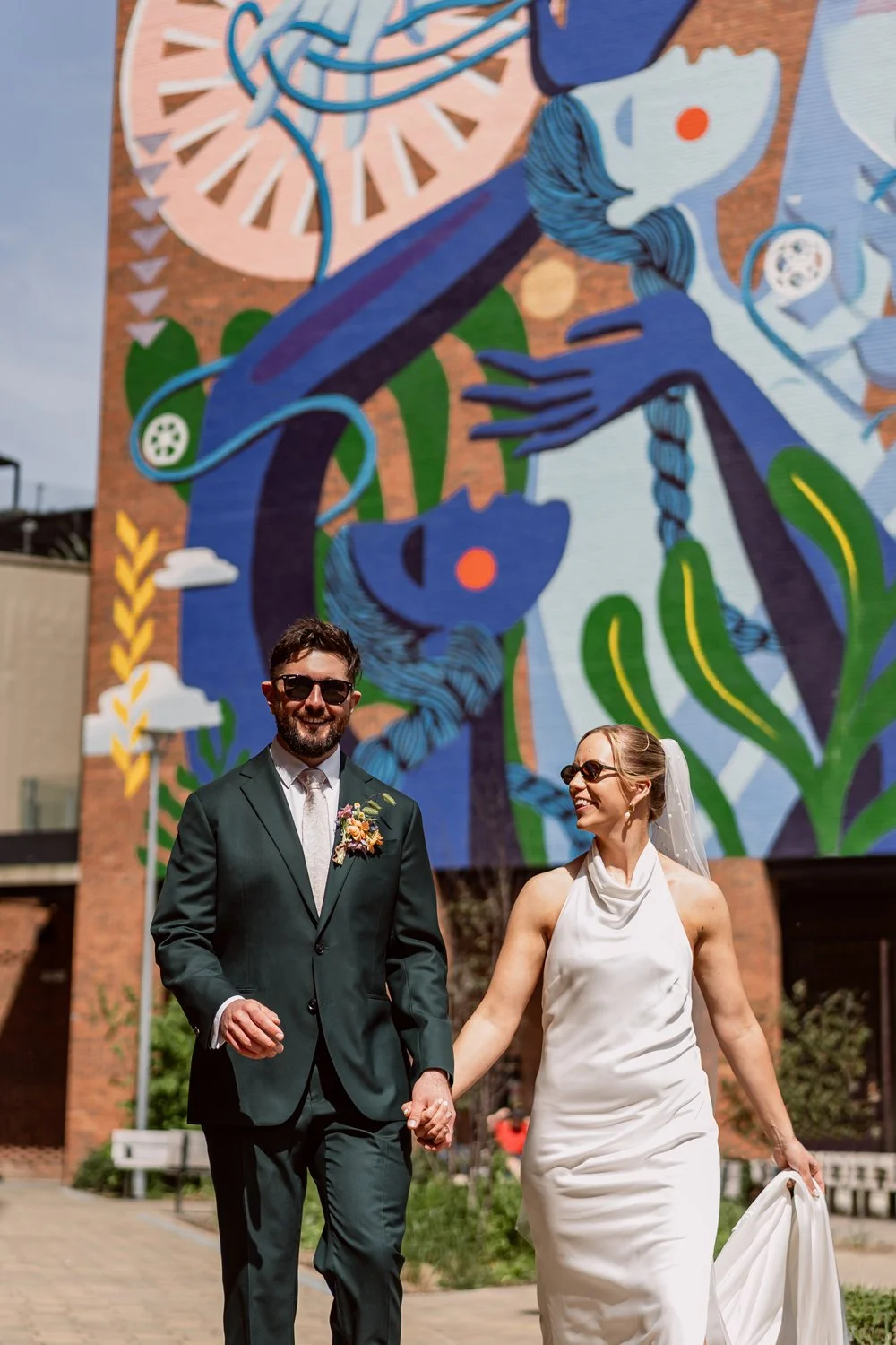Bride and groom walking and smiling with graffiti in the background on their Leeds wedding day