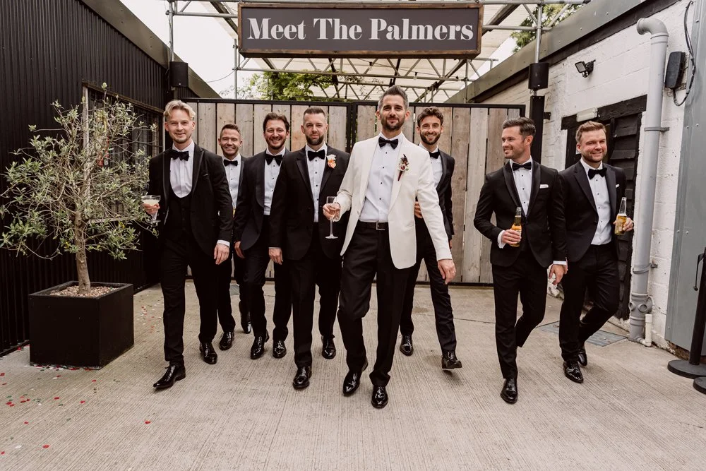 groom and groomsmen walking toward camera laughing 