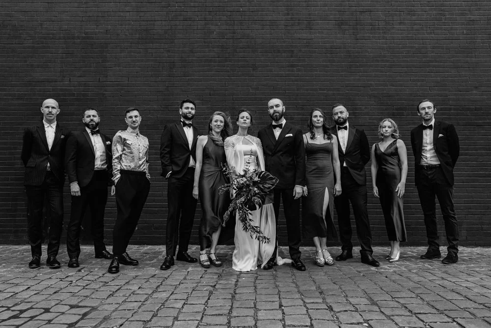 Bride and groom with their bridesmaids and groomsmen in a moody group photo on their wedding in Birmingham