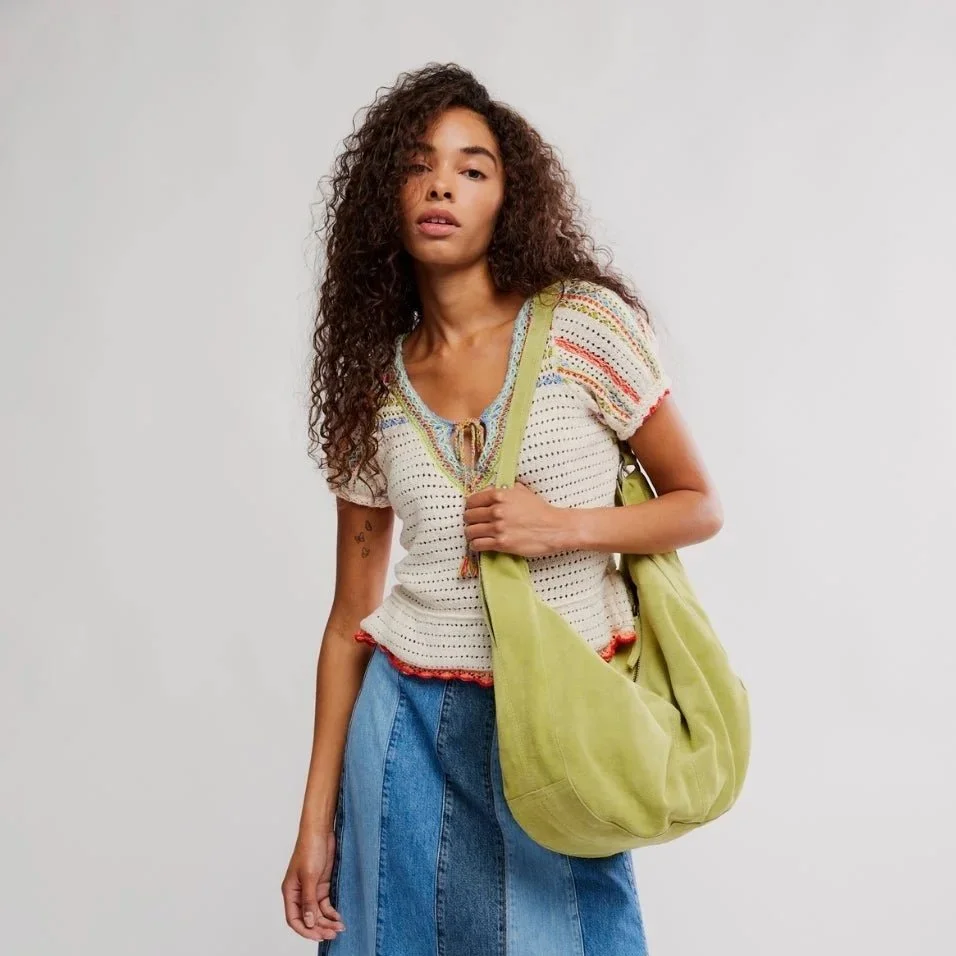 Spring fashion in Providence: a model wearing a jean skirt and a short sleeved knit top while styling a light green tote bag.