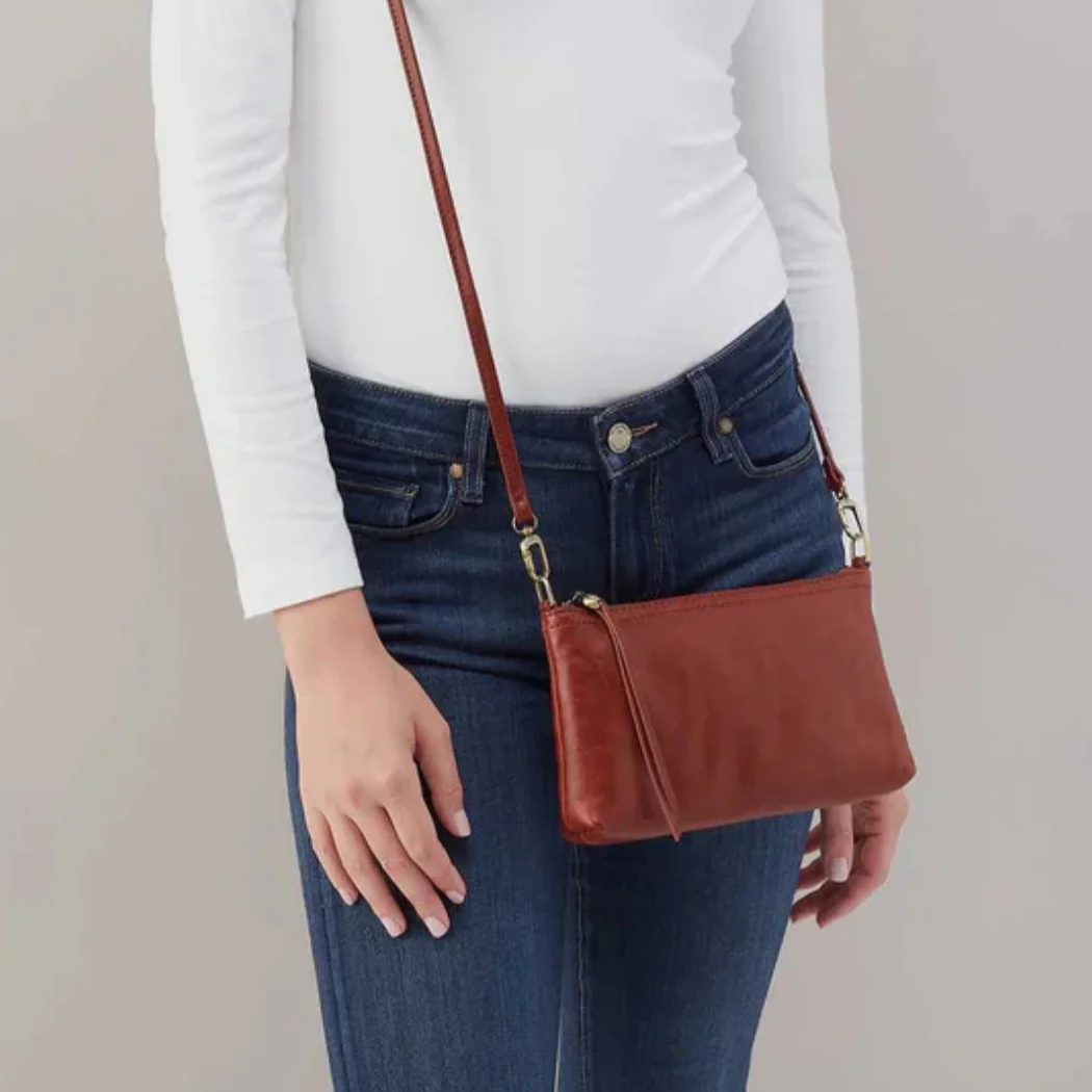 Spring fashion in Providence: A brown crossbody bag modeled by someone wearing jeans and white long sleeved shirt.