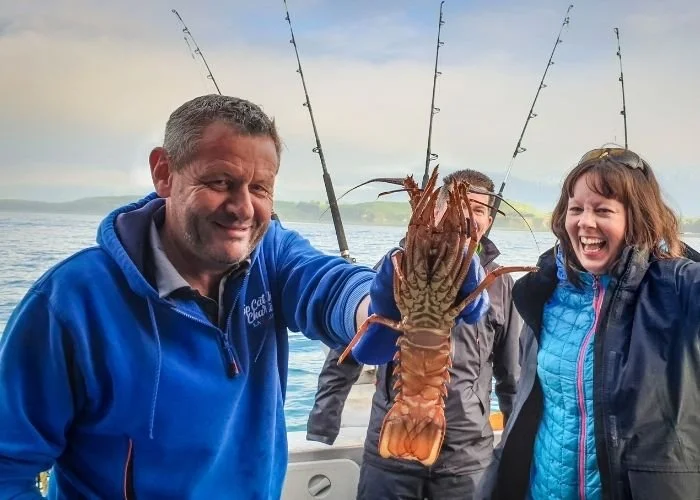 Malcolm from Top Catch Charters holding a crayfish, Kaikoura, New Zealand