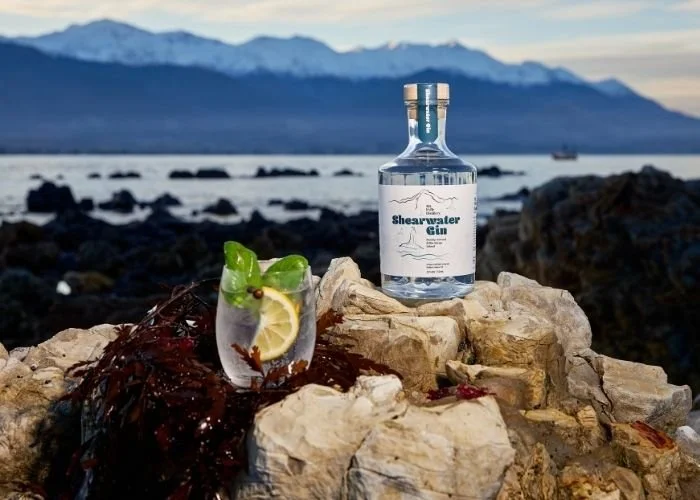 Mt Fyffe Distillery's Shearwater gin in front of the Kaikoura coast and mountains