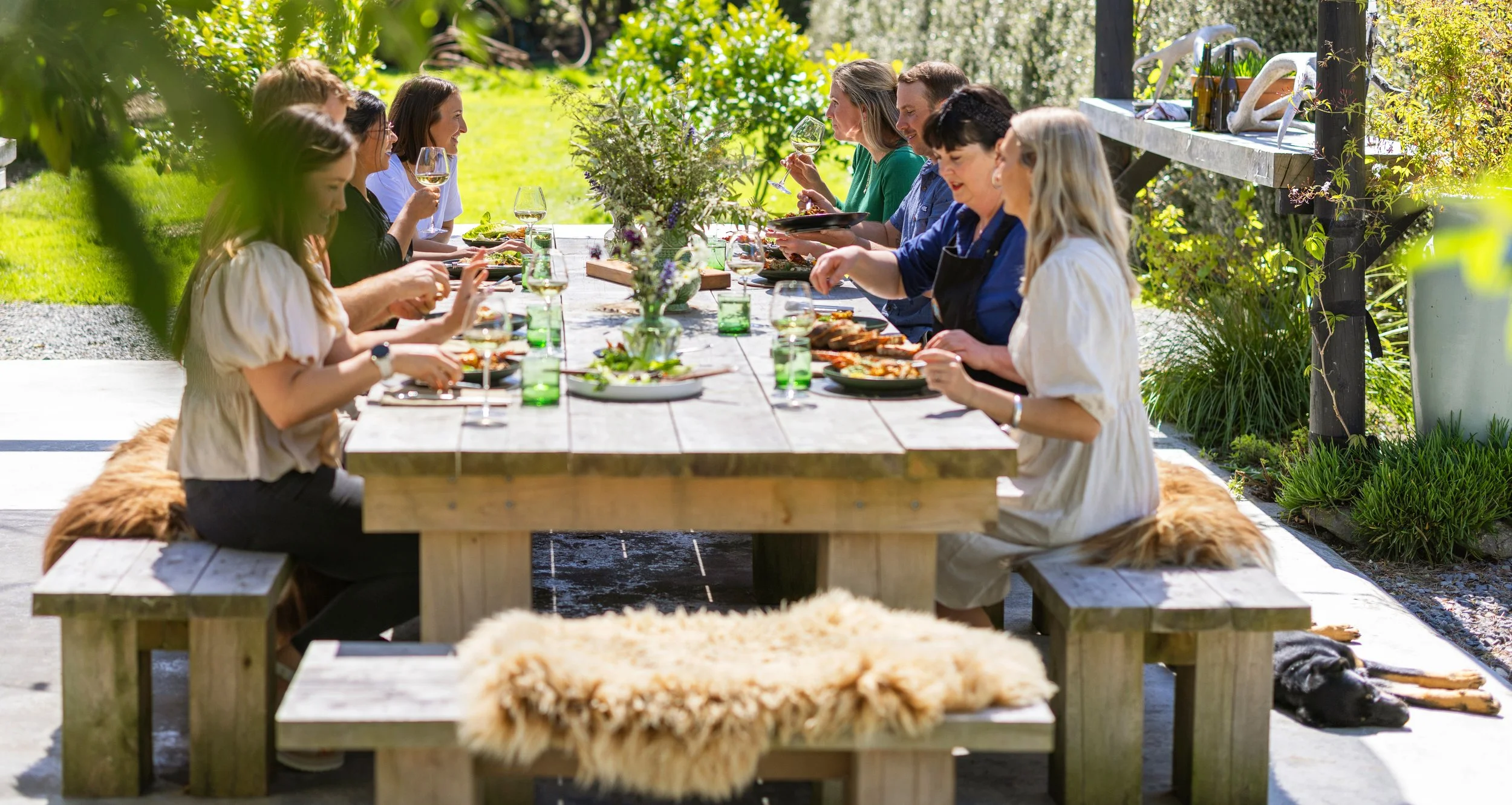 Guests enjoying a seasonal lunch outdoors in the sun at Hapuku Kitchen Cooking School, Kaikōura