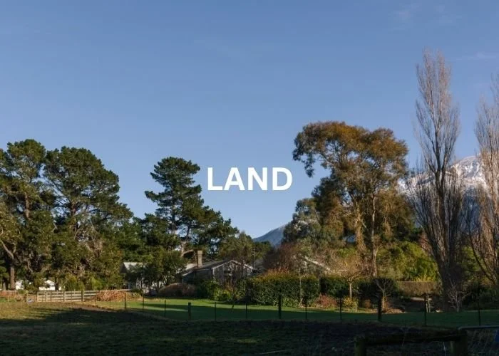 View of Hapuku Kitchen farm with trees and snow-capped mountains, Kaikoura