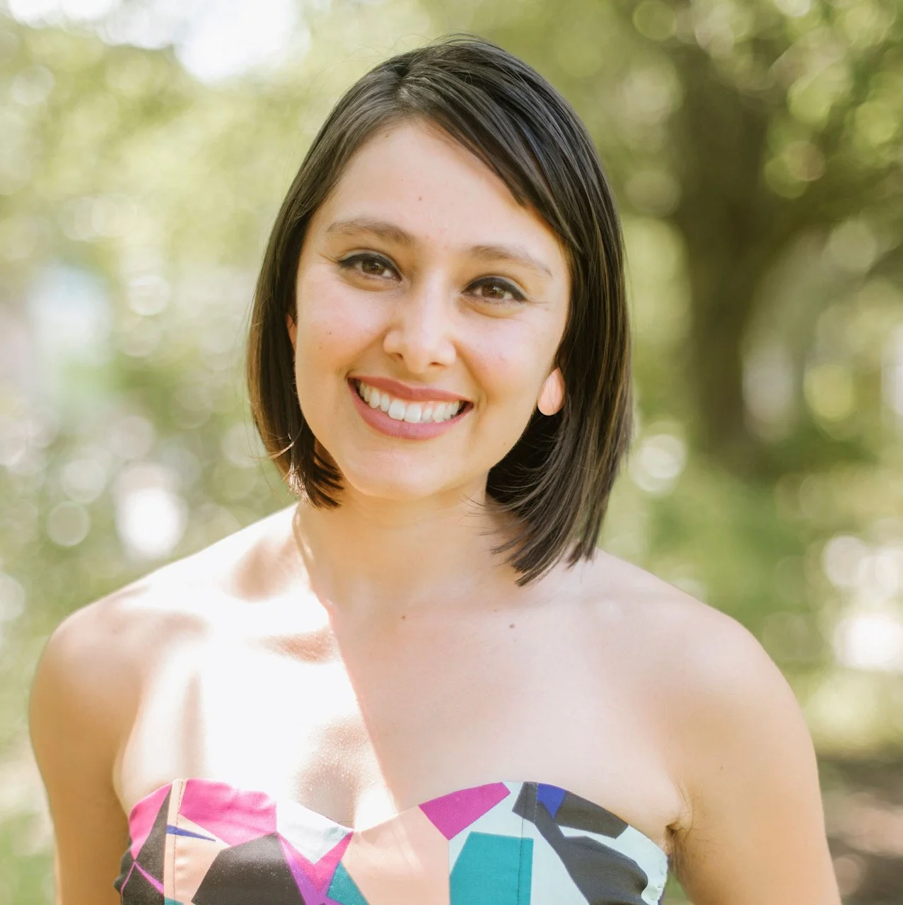 Head shot of a female with a blurry green outside scenary background and a blue button down. Big smile, short blonde hair, light skinned. Program Coordinator & ACT Instructor.