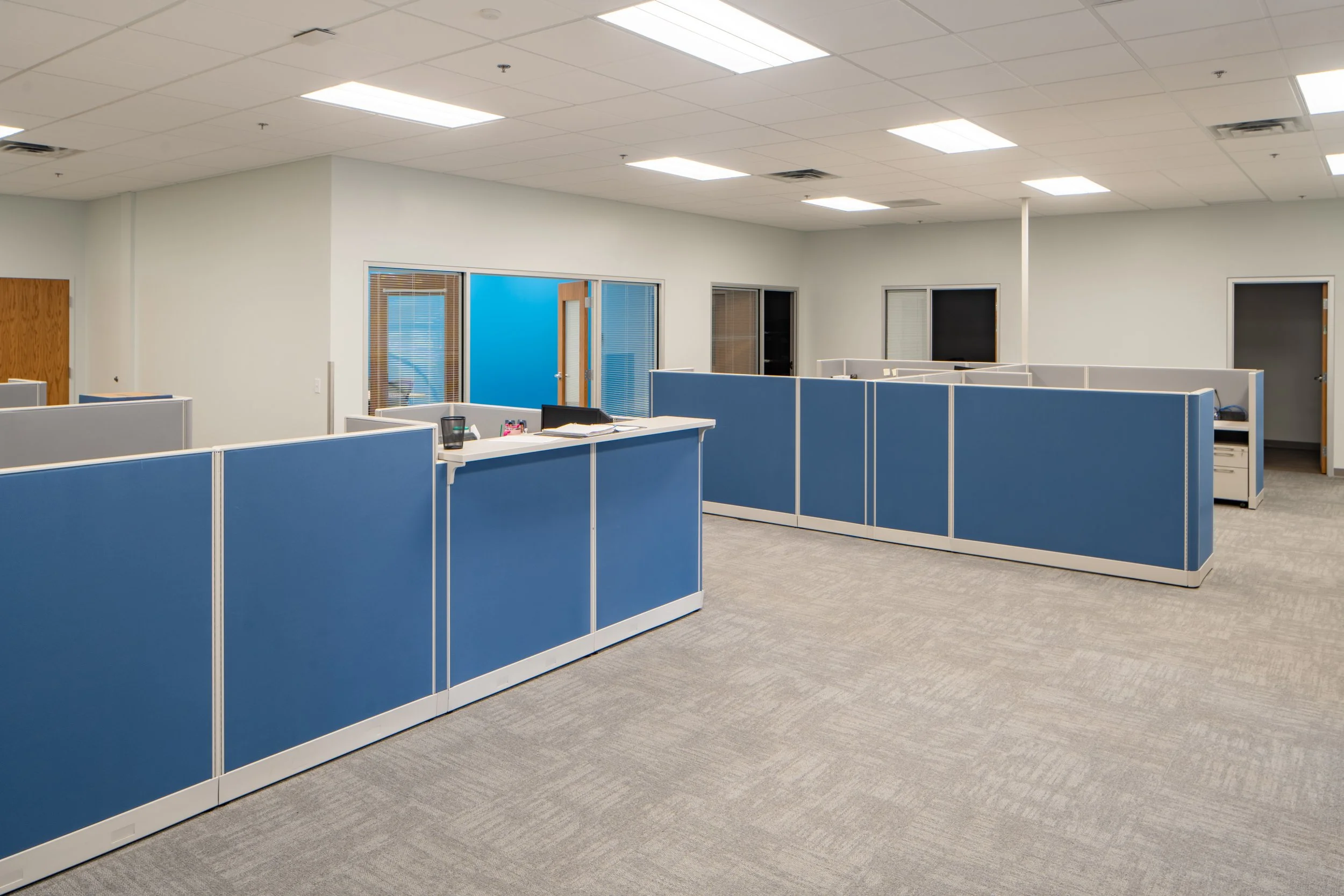 Open office buildout featuring modular cubicles, carpet tile, and enclosed meeting rooms.