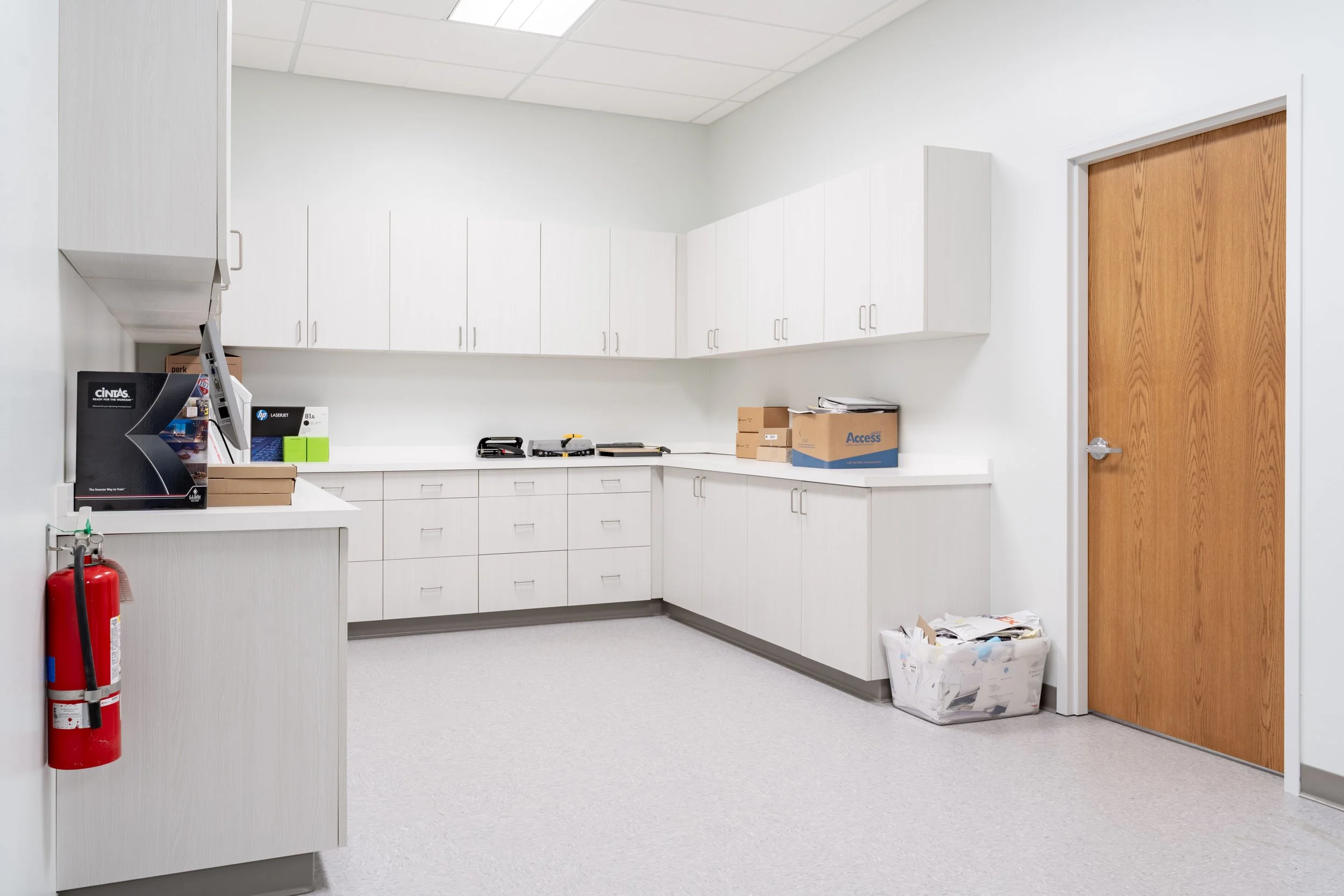 Completed office support room with custom white cabinetry, durable flooring, and organized commercial storage.