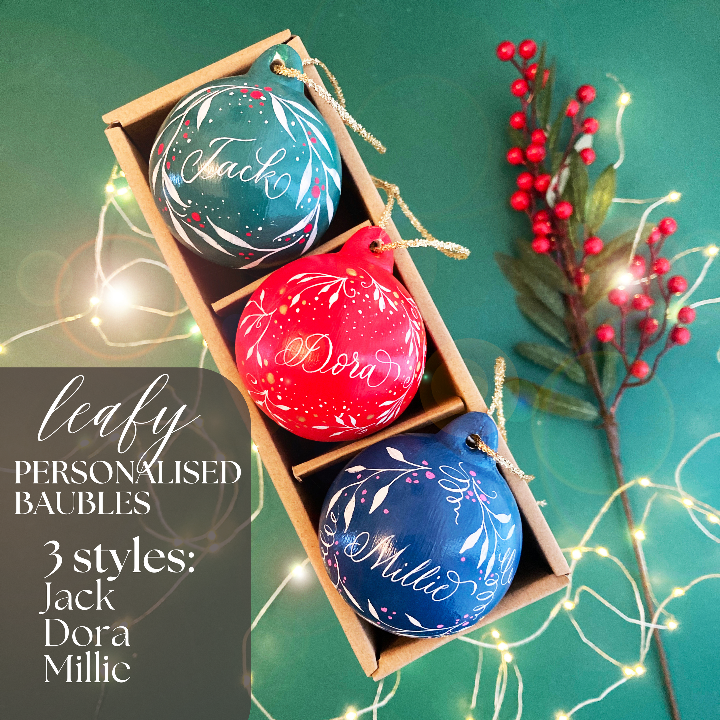 3 christmas baubles in a box. They have names written on in lovely handwriting and they're painted with leaves and berries