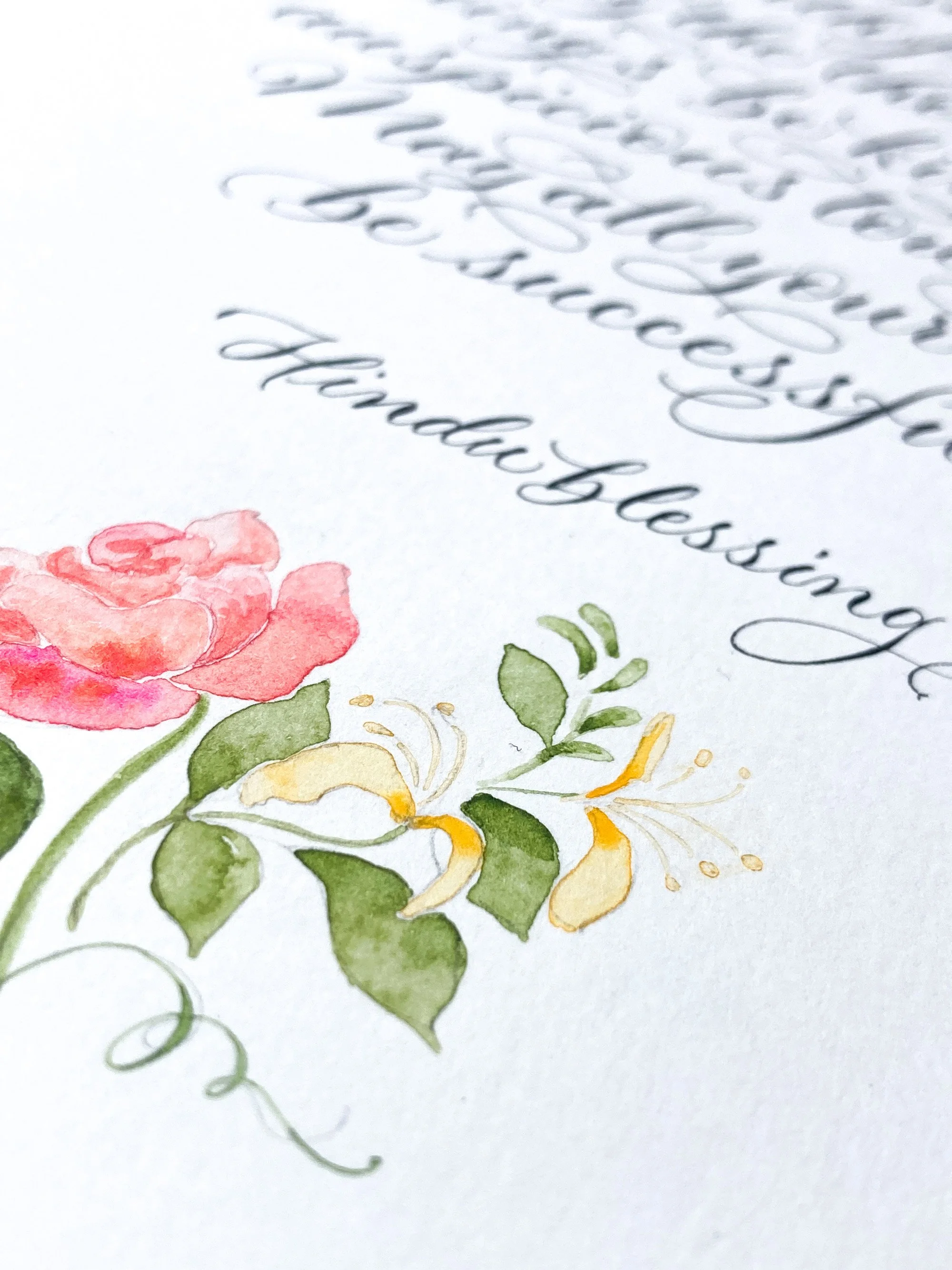 Close-up of a wedding blessing commission in hand calligraphy and watercolour floral design featuring pink and yellow flowers with green leaves.