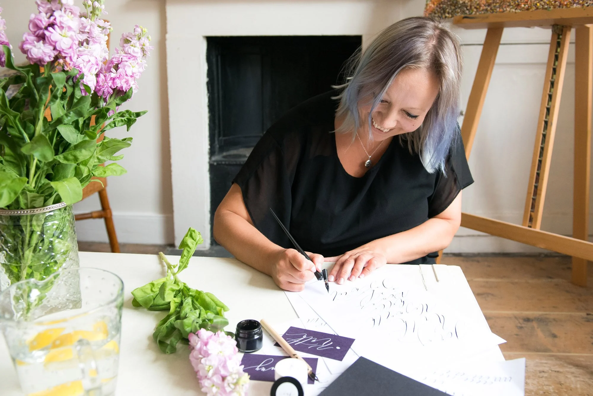 Claire Gould writing calligraphy in the north west UK. Claire's smiling and using an oblique penholder to write a page of modern calligraphy