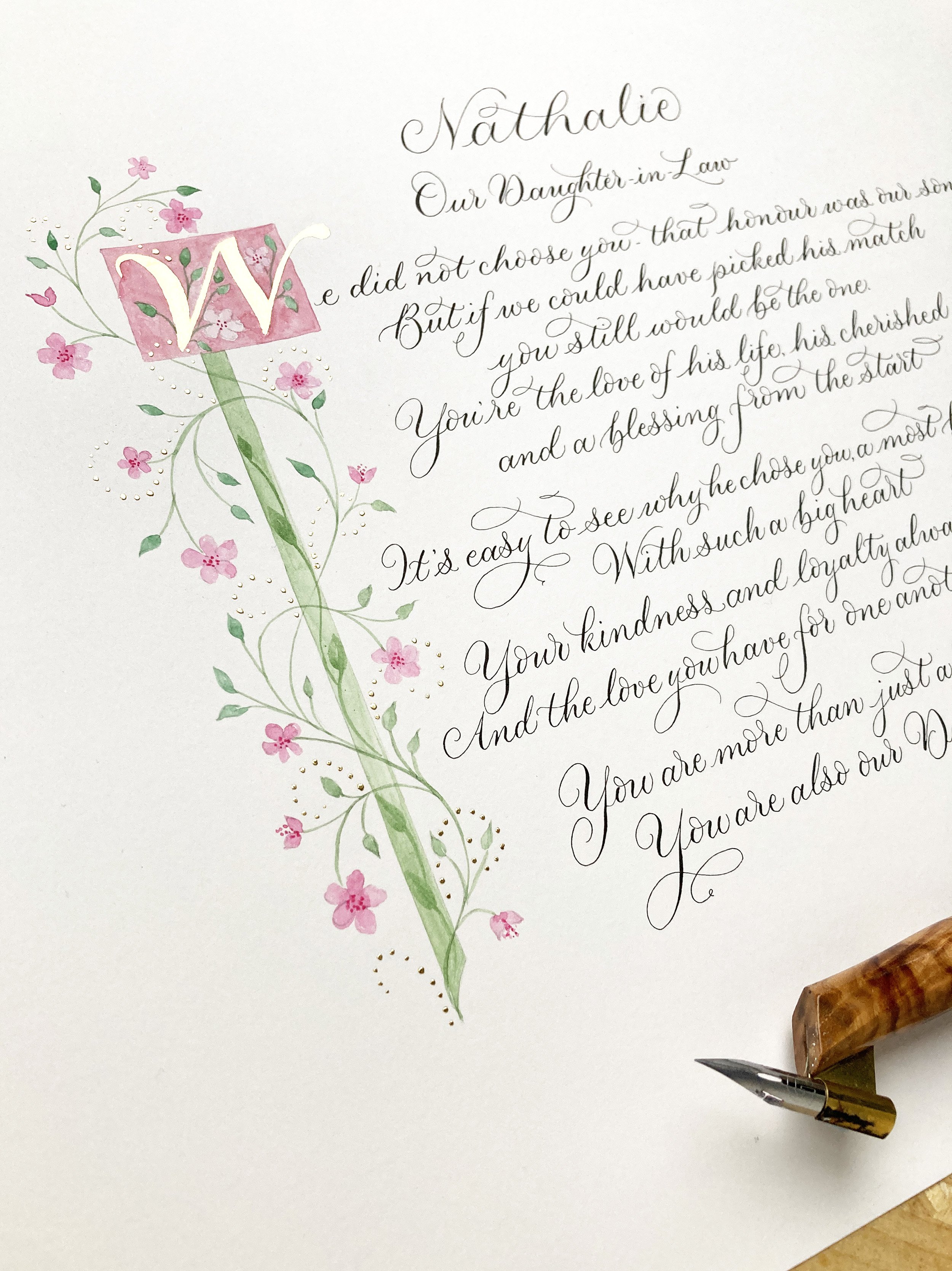 Calligraphy poem with illustrated pink flower and gold leaf border and lettering in a modern copperplate style