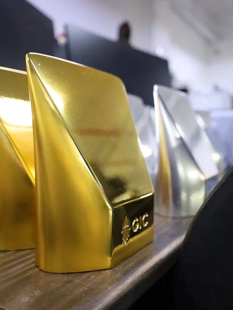 Close-up of gold and silver trophies with a sleek, modern design on a wooden surface.
