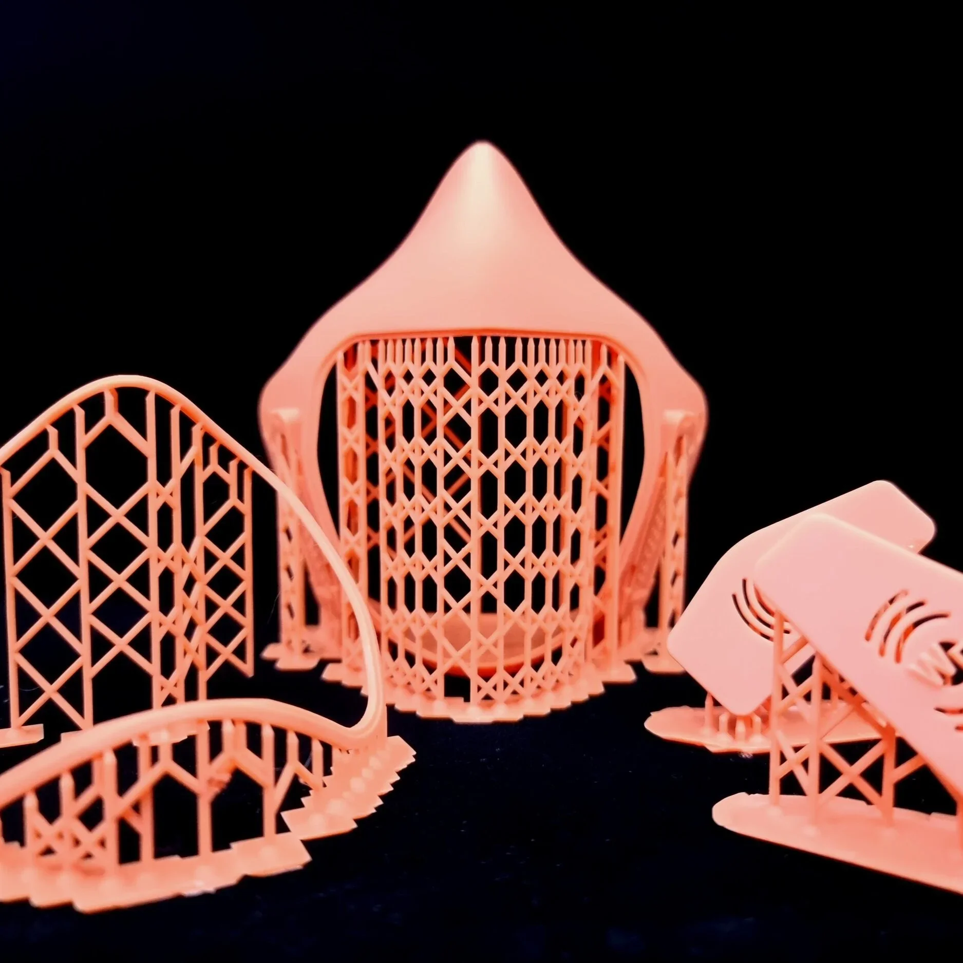 Pink plastic architectural model pieces arranged on a black background.