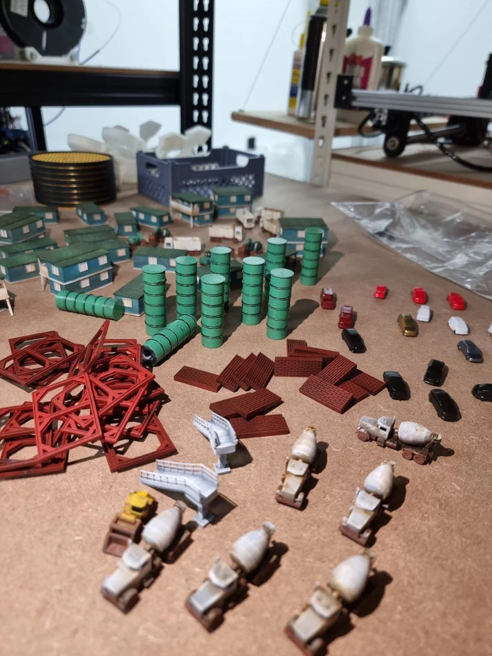 Model train set with miniature buildings, cars, and construction equipment arranged on a table.