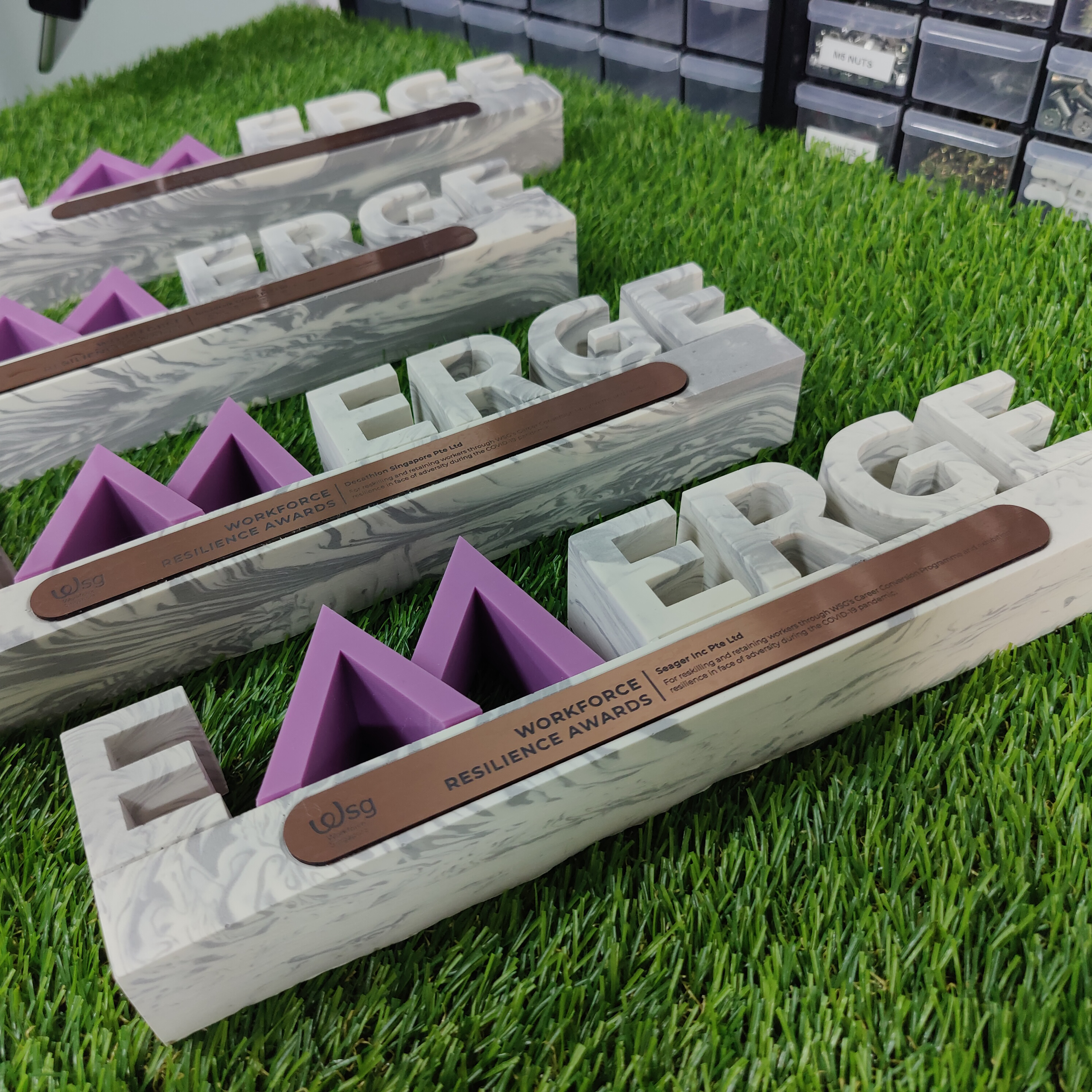 Awards in marble-style boxes with purple triangular awards in bright green grass display.