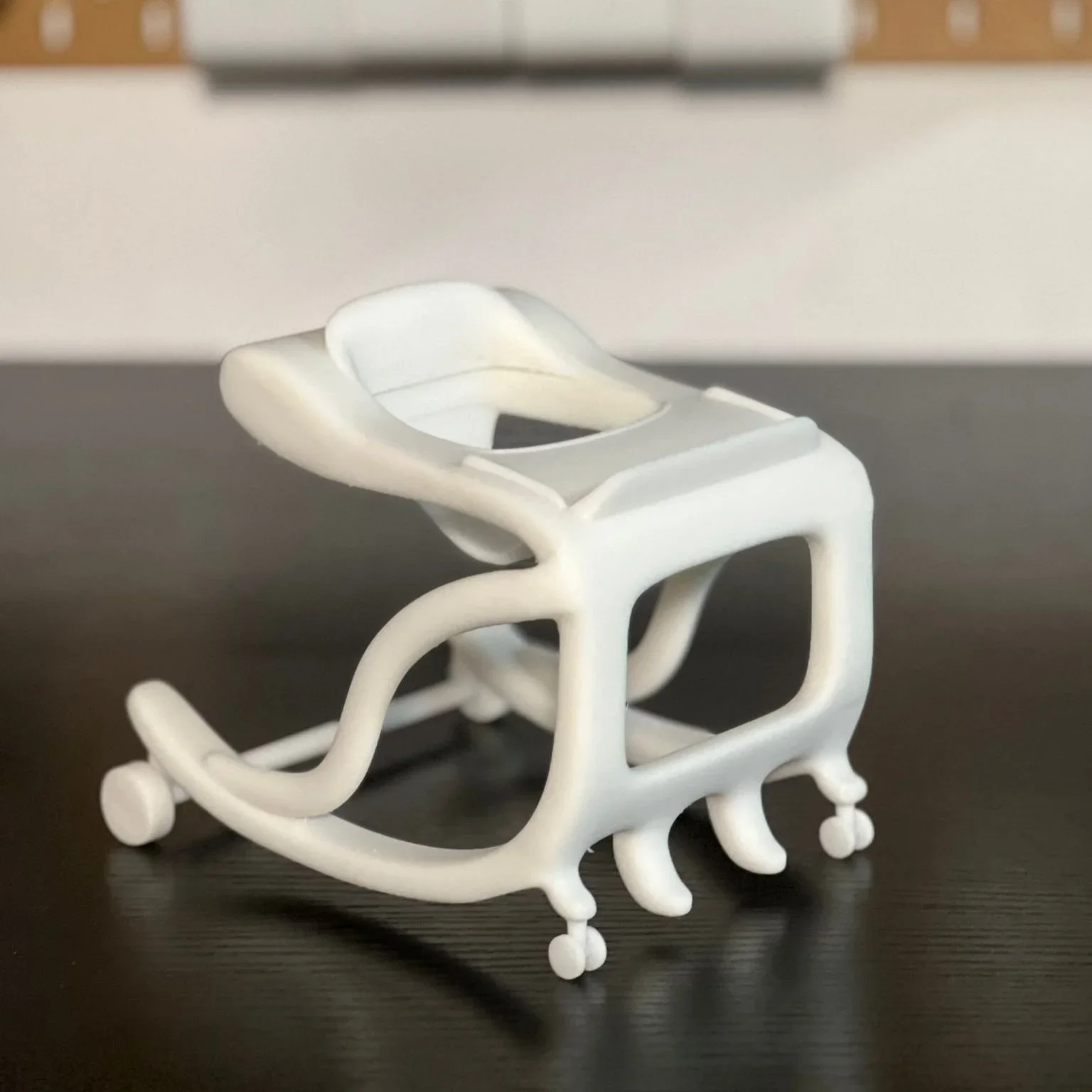 White plastic medical cap with an open top, designed for a small patient or doll, placed on a dark surface.