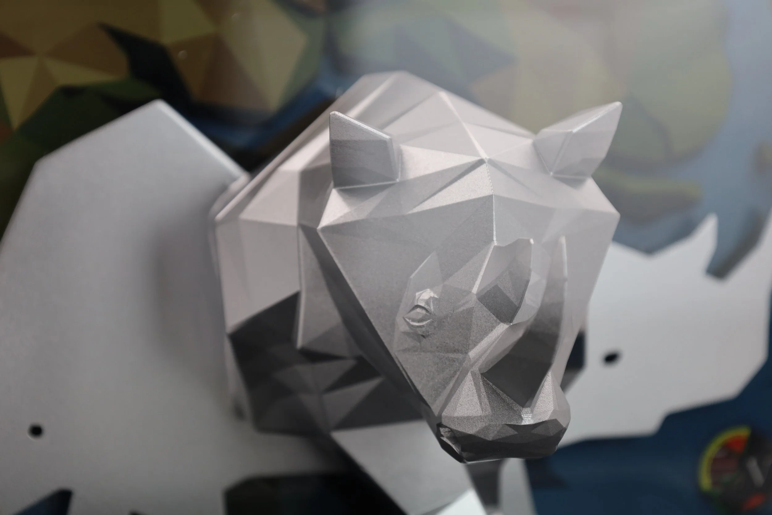 Three quarter view of a 3D printed silver rhino on a black base plate with a metal name plate, encased in an acrylic box
