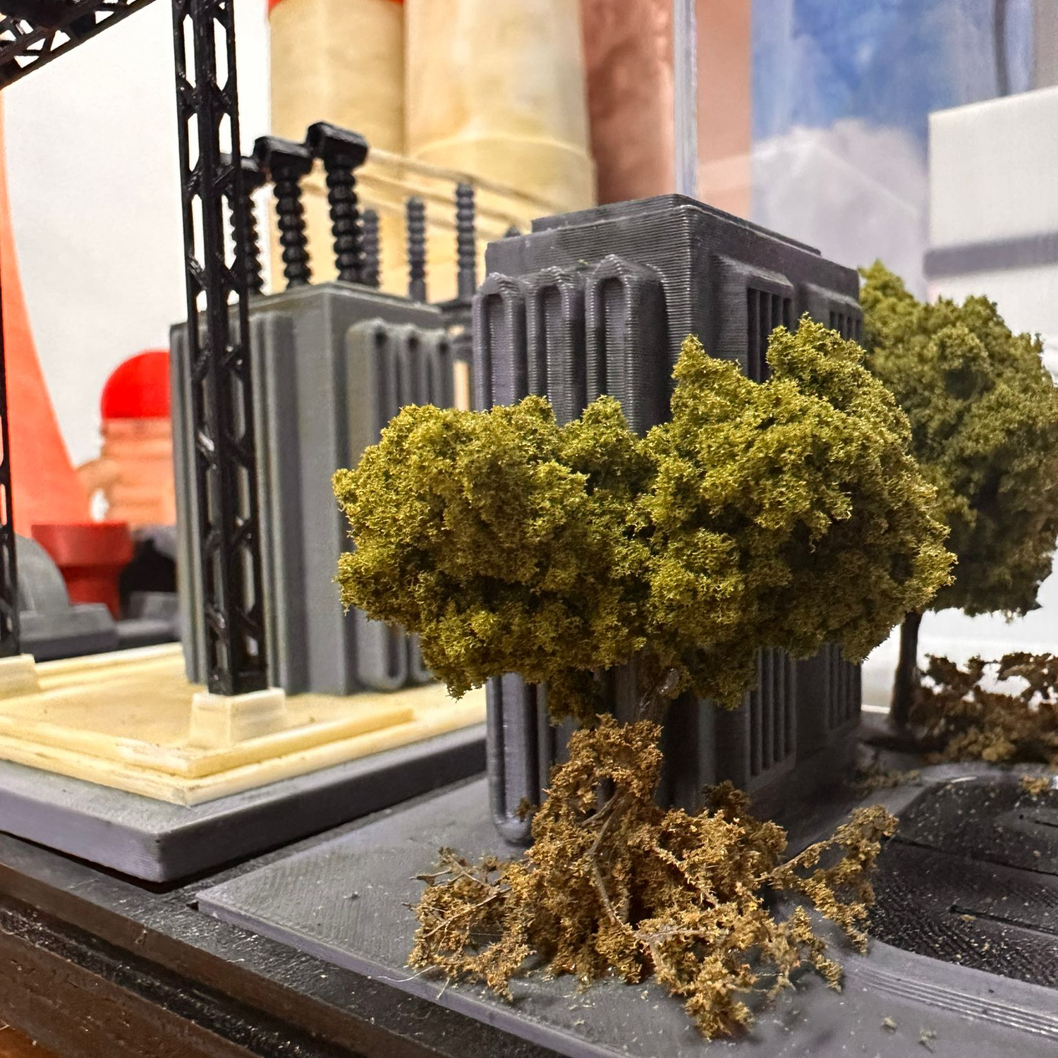 Miniature model of a city scene with buildings, trees, and fences.
