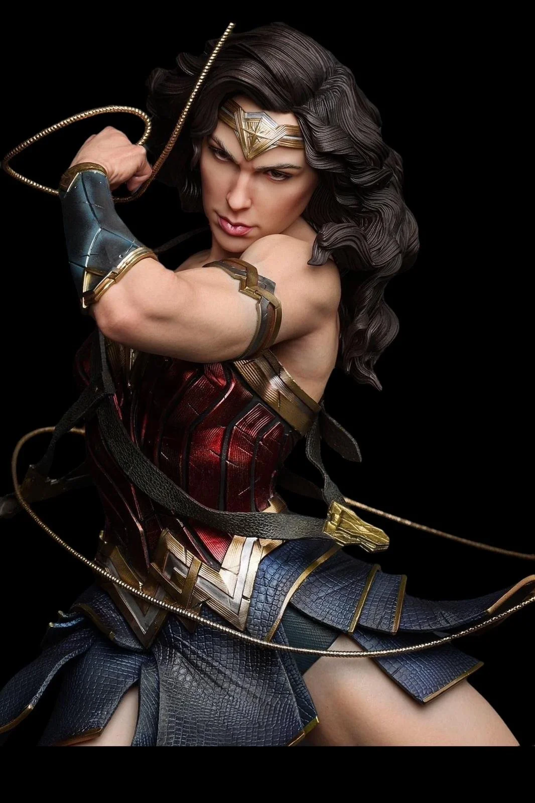 A woman dressed as Wonder Woman in a detailed costume holding a lasso, with a black background.