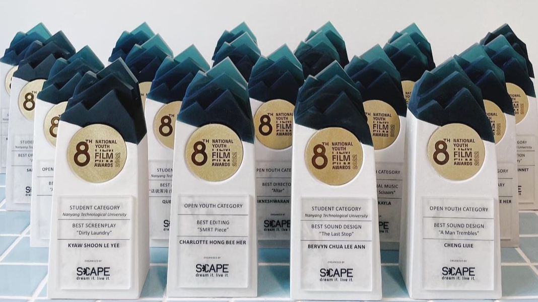 Multiple award trophies for the 8th National Youth Film Awards arranged on a table.
