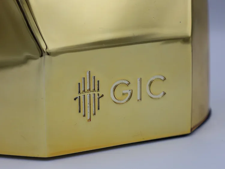 Close-up of a gold-colored object with a logo and the text GIC engraved on it