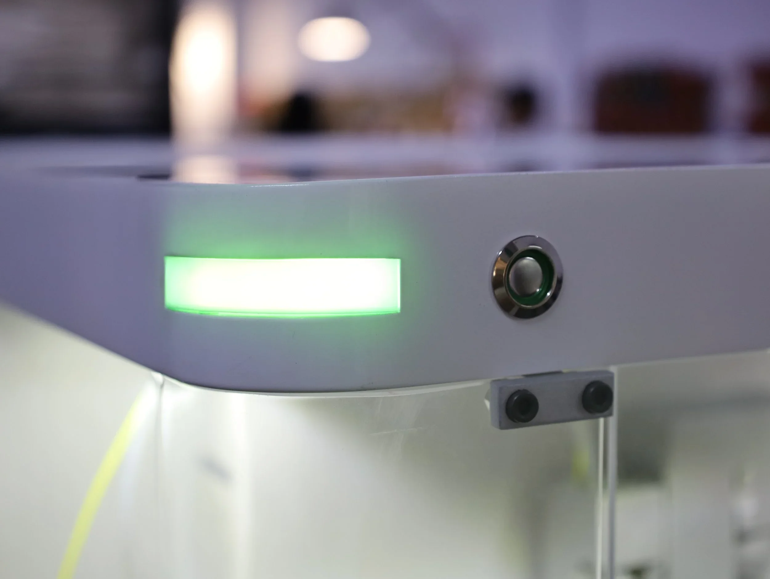 Close-up of a laboratory or medical device with a green illuminated display and a circular metallic button.