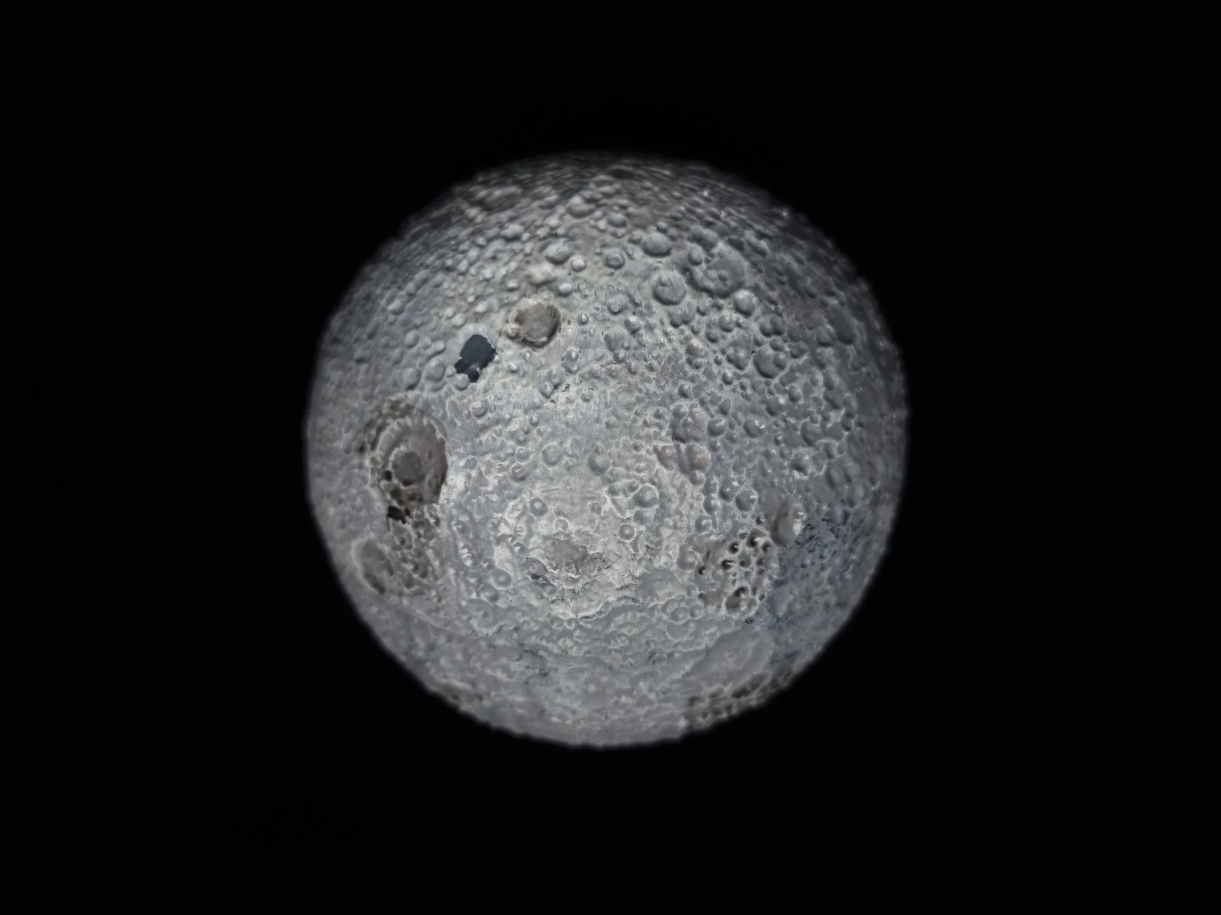 Close-up of the moon's surface showing craters, illuminated against a black background.