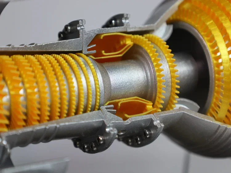 Close-up of a mechanical device with yellow gear-like components and metal parts.