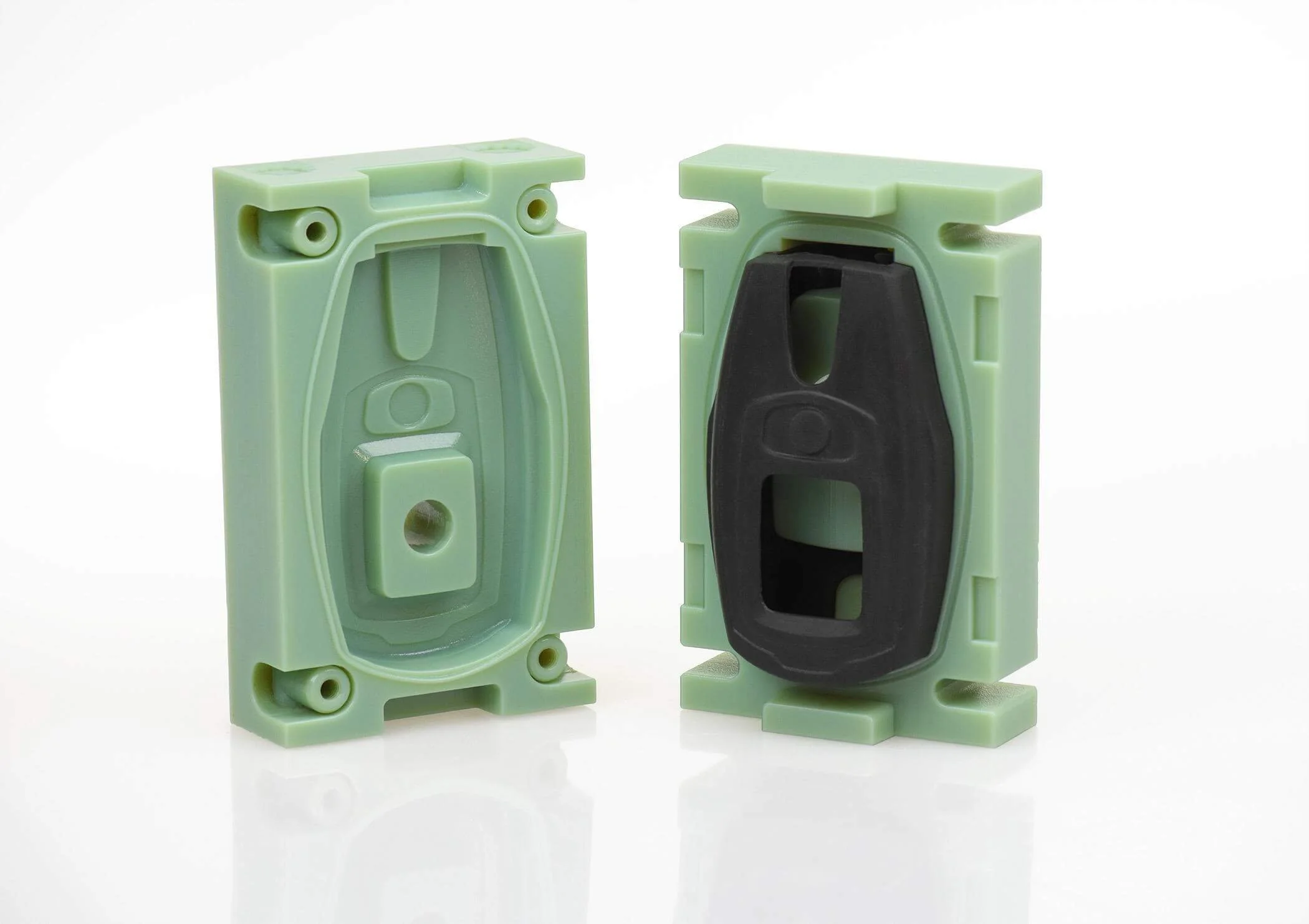 Two green electrical outlet boxes, one with a black rubber gasket inside, against a white background.