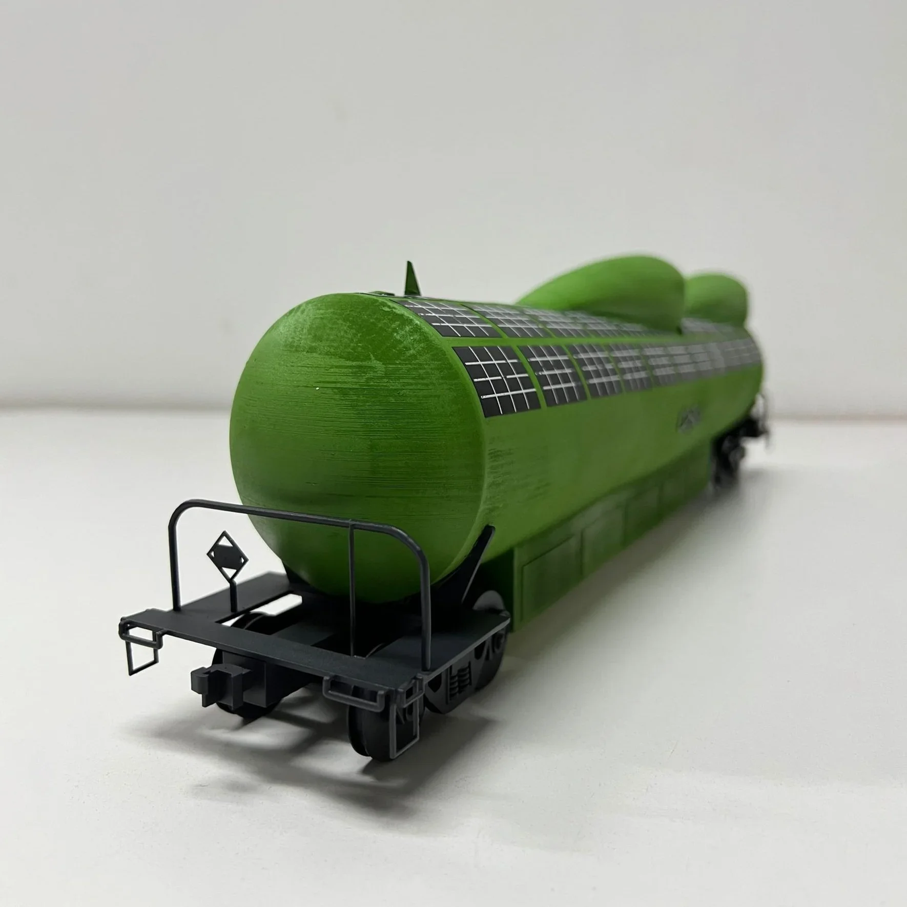 Green model train with solar panel design on a plain white surface.
