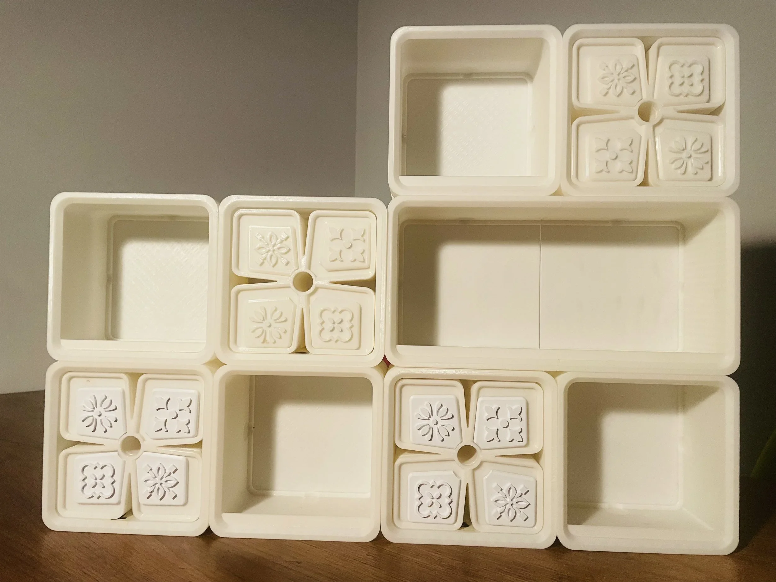 Multiple empty white plastic cubes of varying sizes stacked together on a wooden surface.