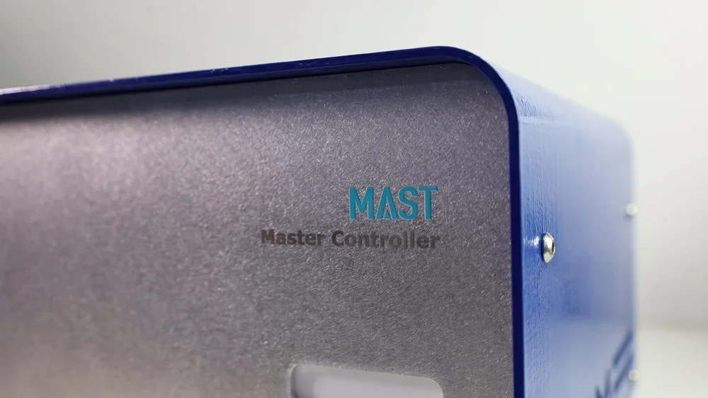 Close-up of a blue and gray electronic device labeled 'MAST Master Controller'.