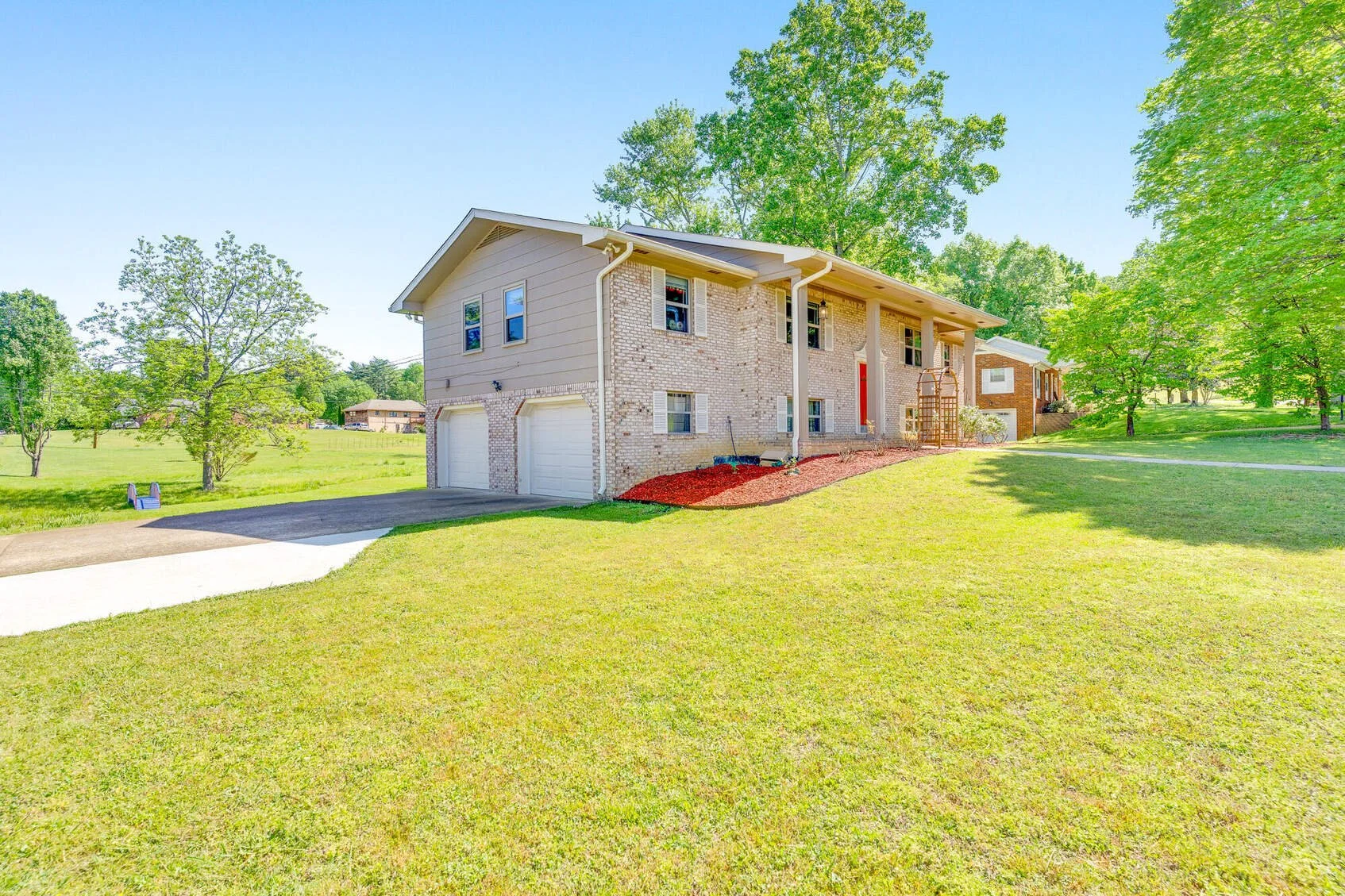 Side of the brick home with the 2-car garage and a large lawn