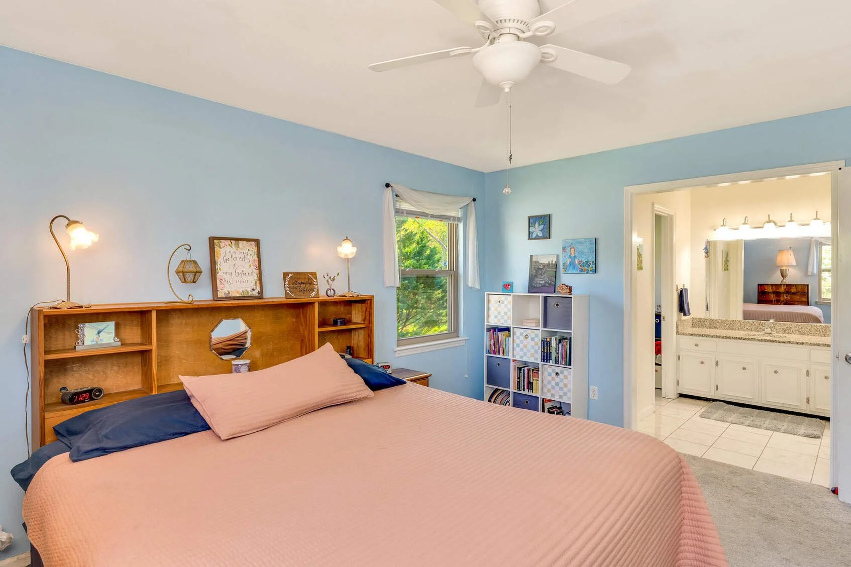Upper-level primary bedroom with ceiling fan and a door to the private bath