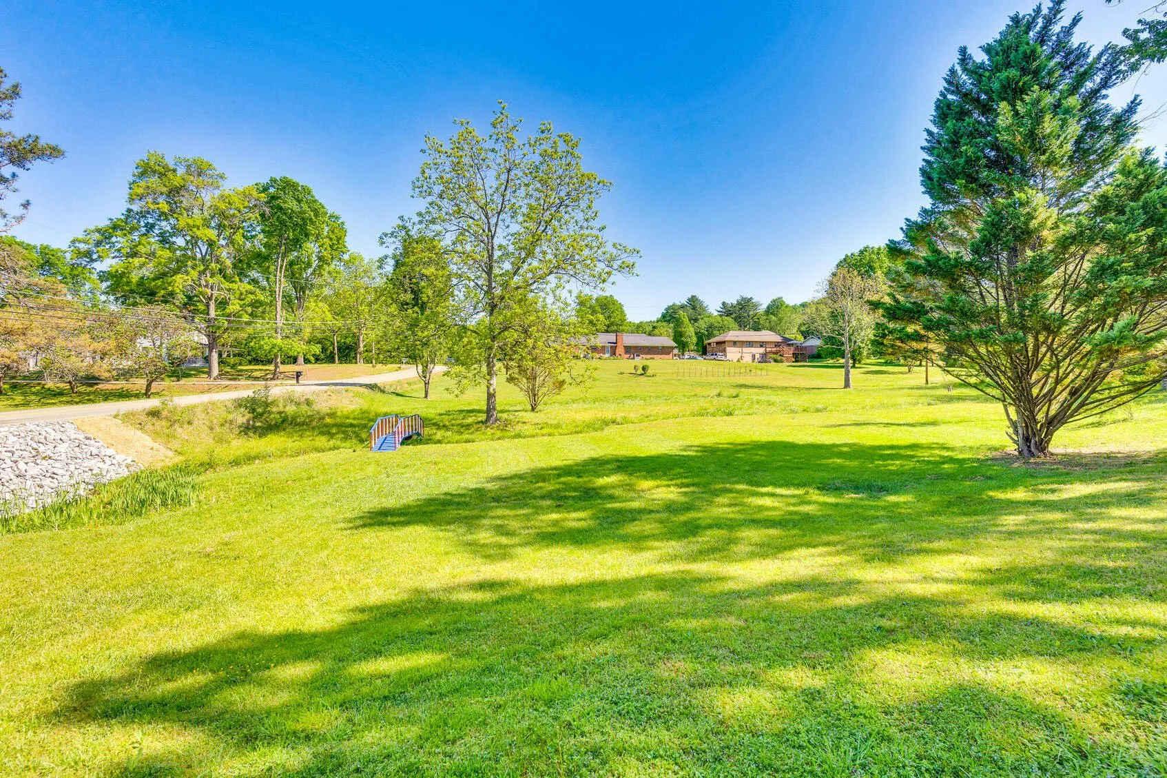 Yard with mature trees and a small footbridge over the creek