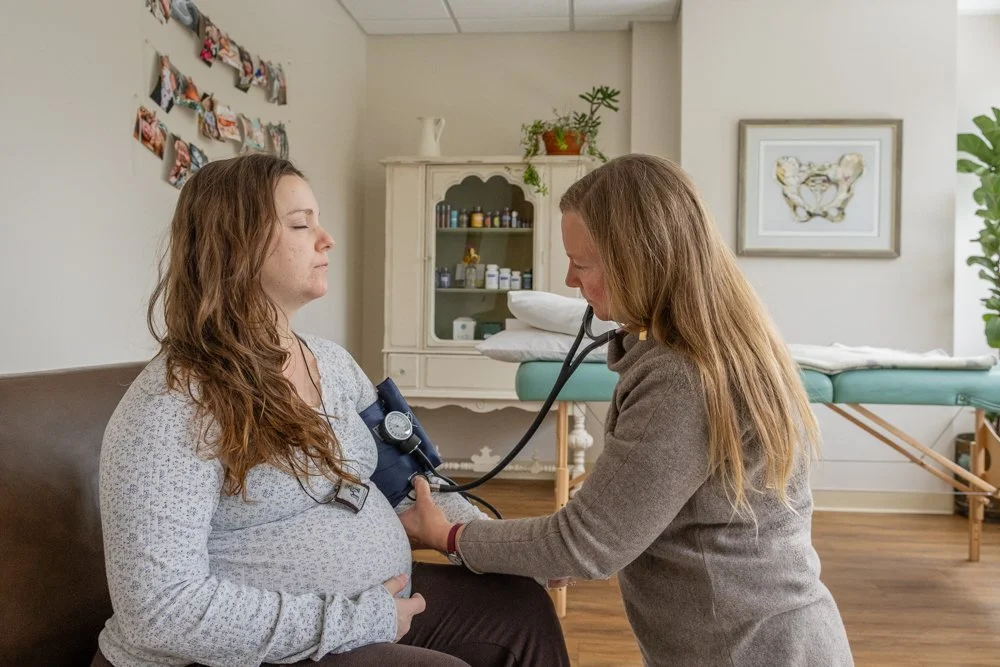 A healthcare professional taking a woman's blood pressure using a sphygmomanometer in a medical office.