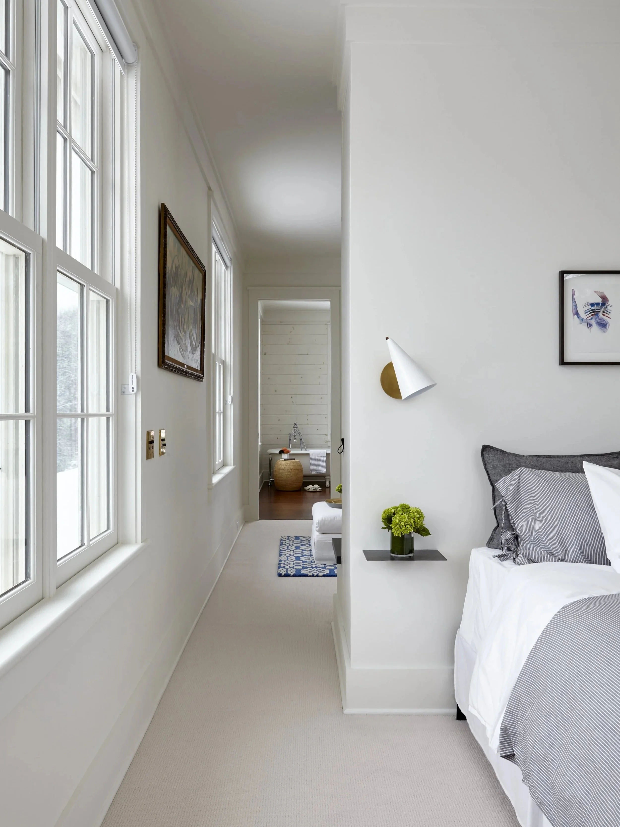 Modern white sconce light next to bed with white and gray sheets