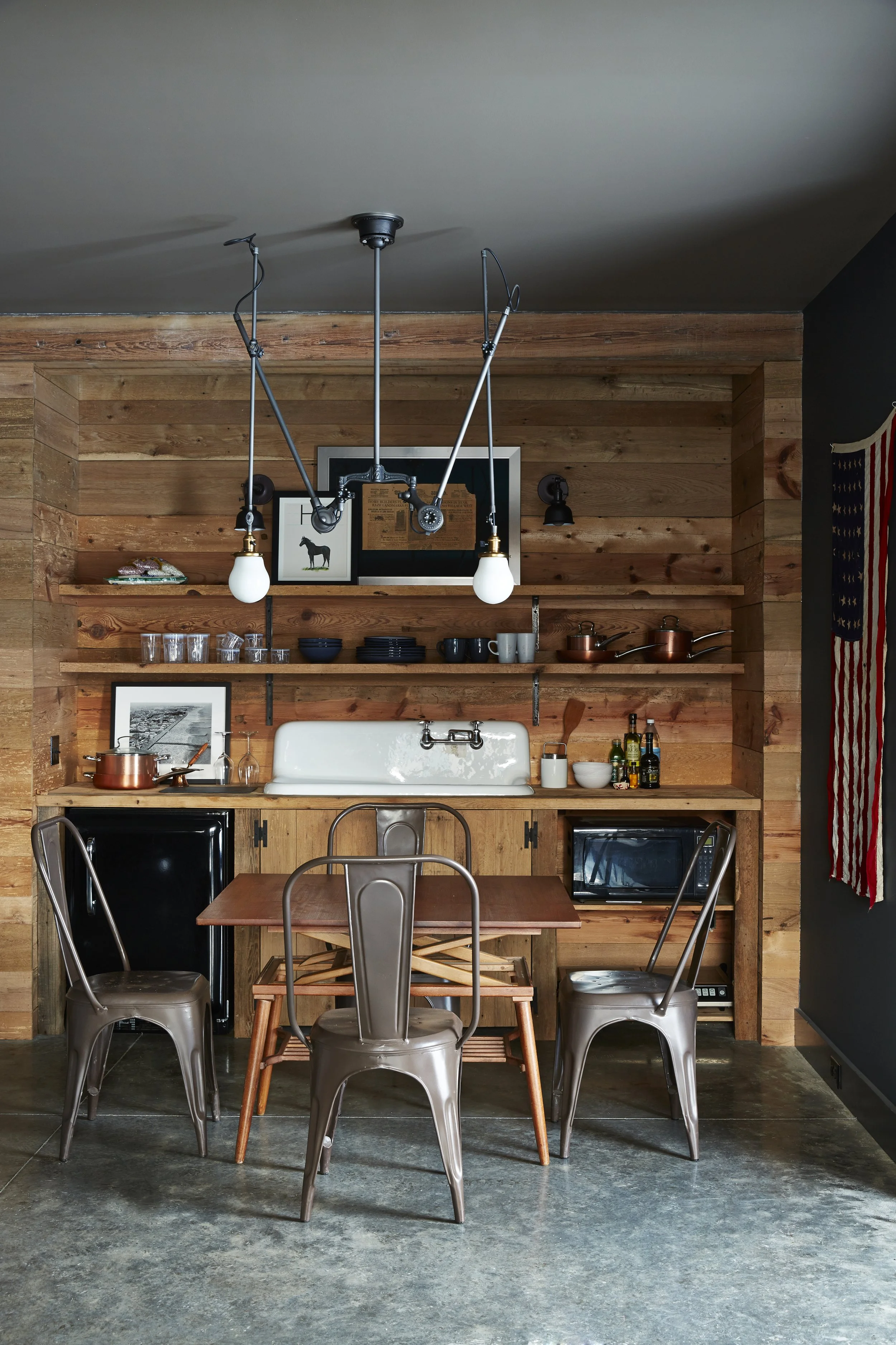 Industrial chandelier light hanging over wood table with metal chairs