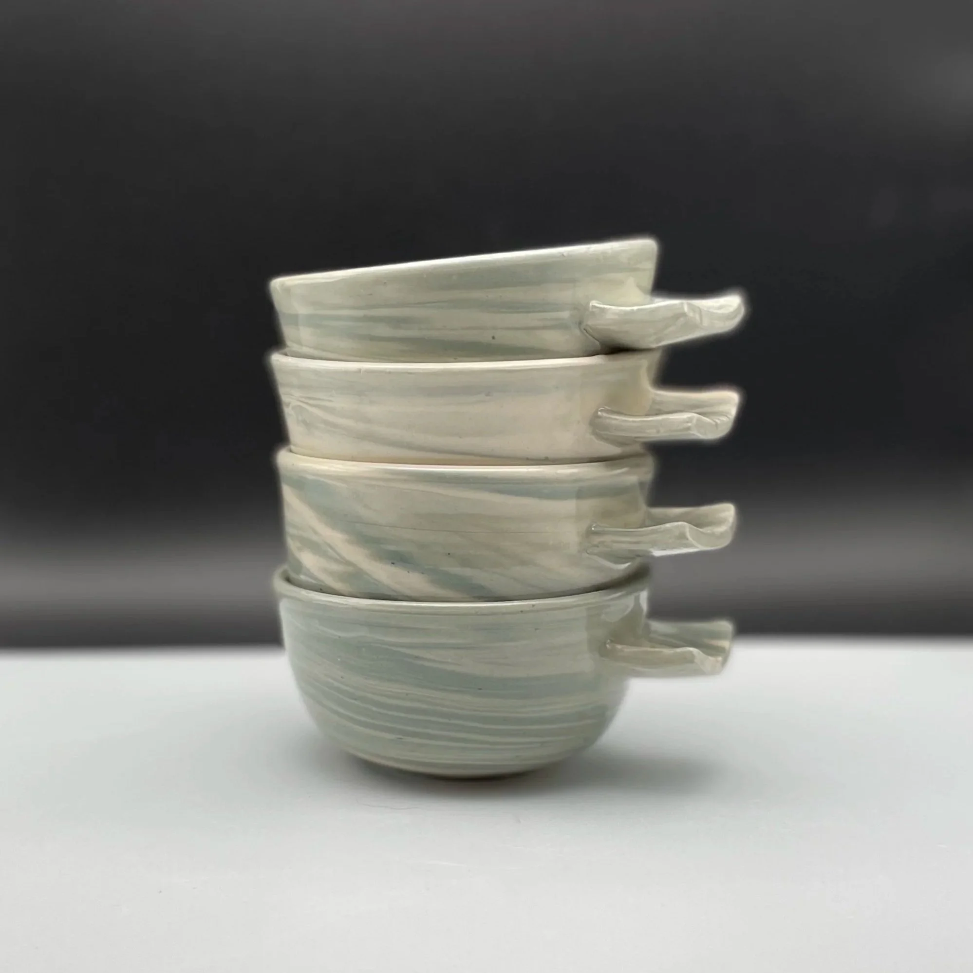 A ceramic jar with a blue lid sitting outdoors on a rocky surface in a desert landscape with dry grasses, rocks, and mountains in the background under a clear blue sky.